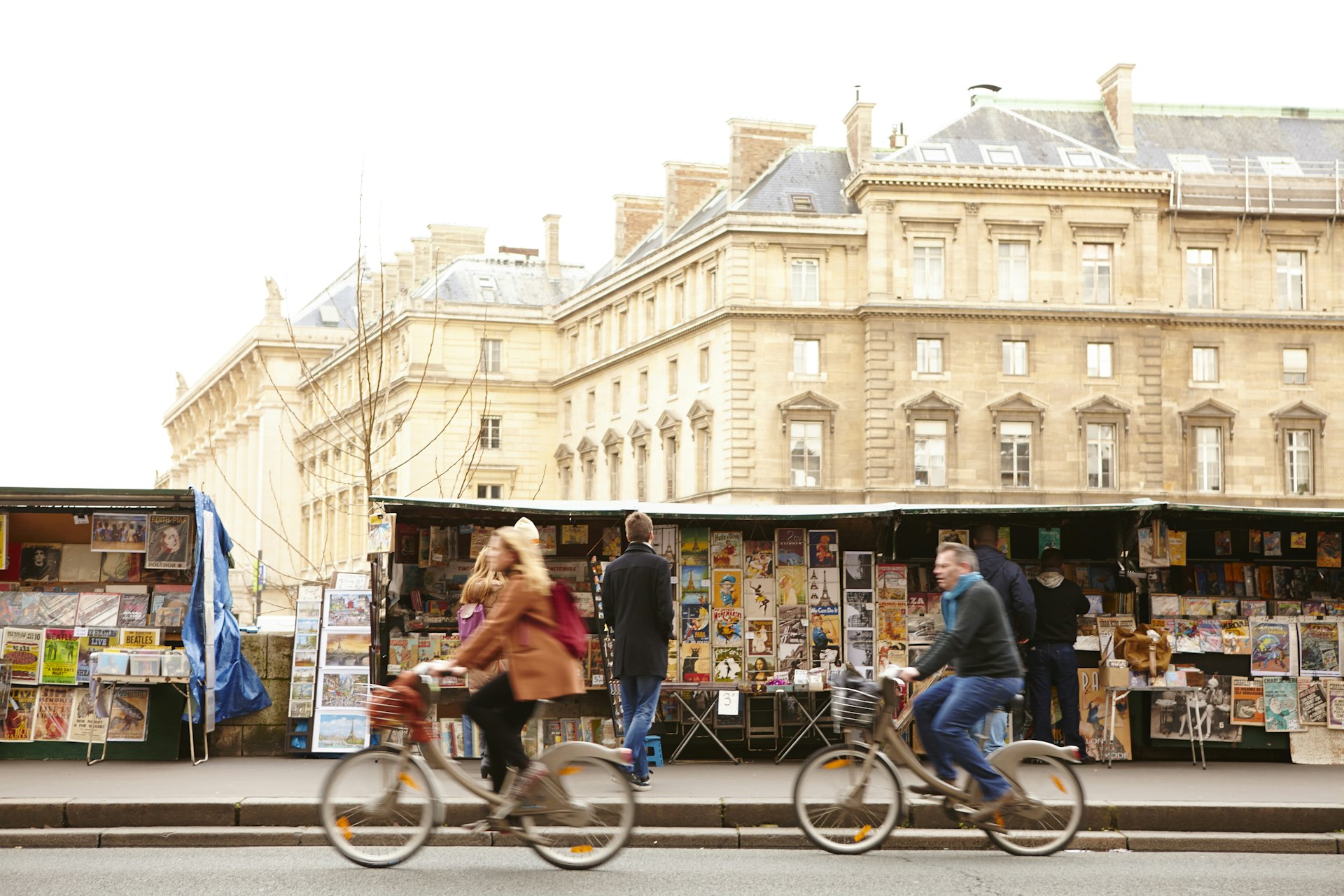 Cyclists passing Bouquinistes (booksellers) on the banks of the Seine. 