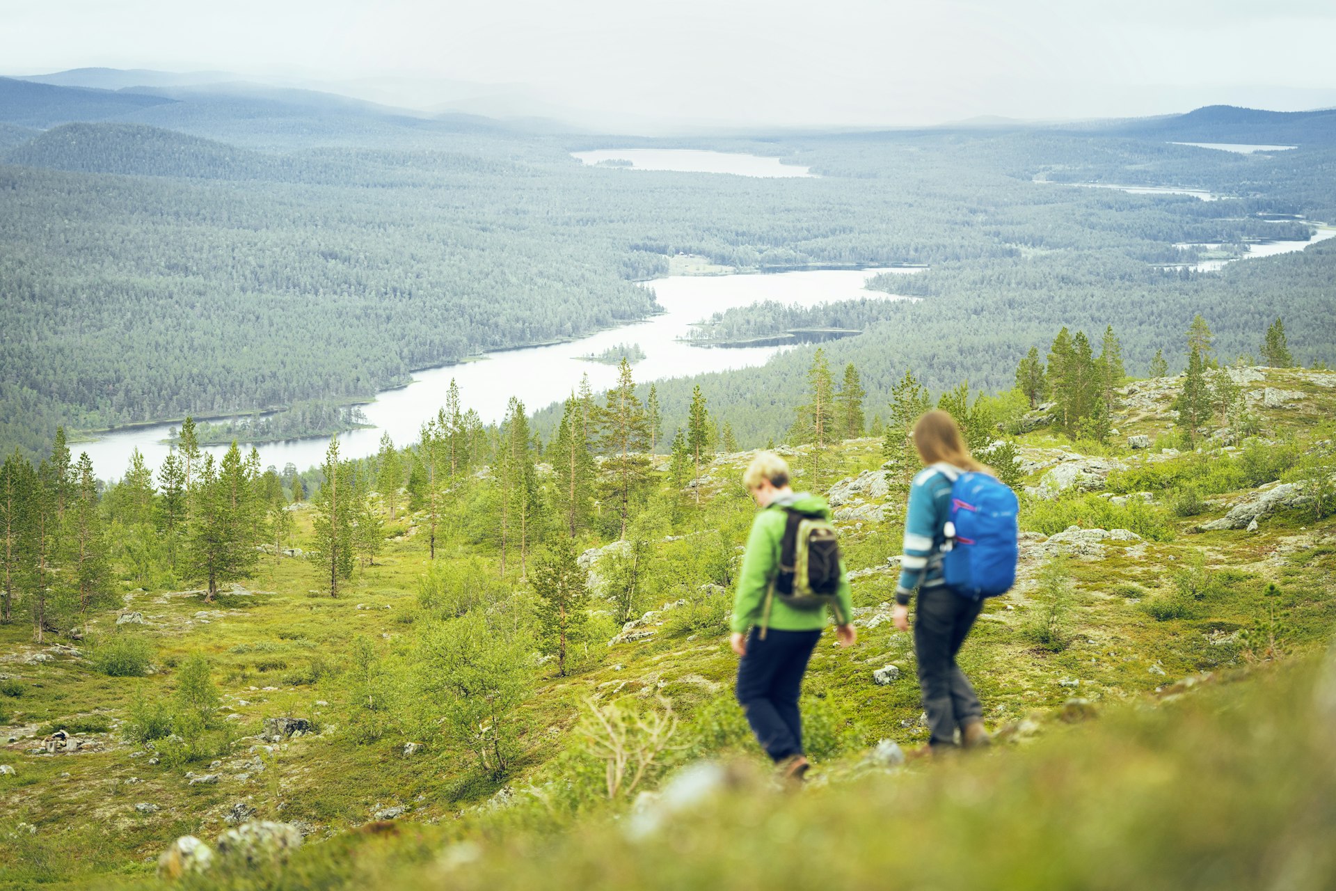 Two women with backpacks make the descent from Sierikniva fell,  Lemmenjoki National Park, Finland