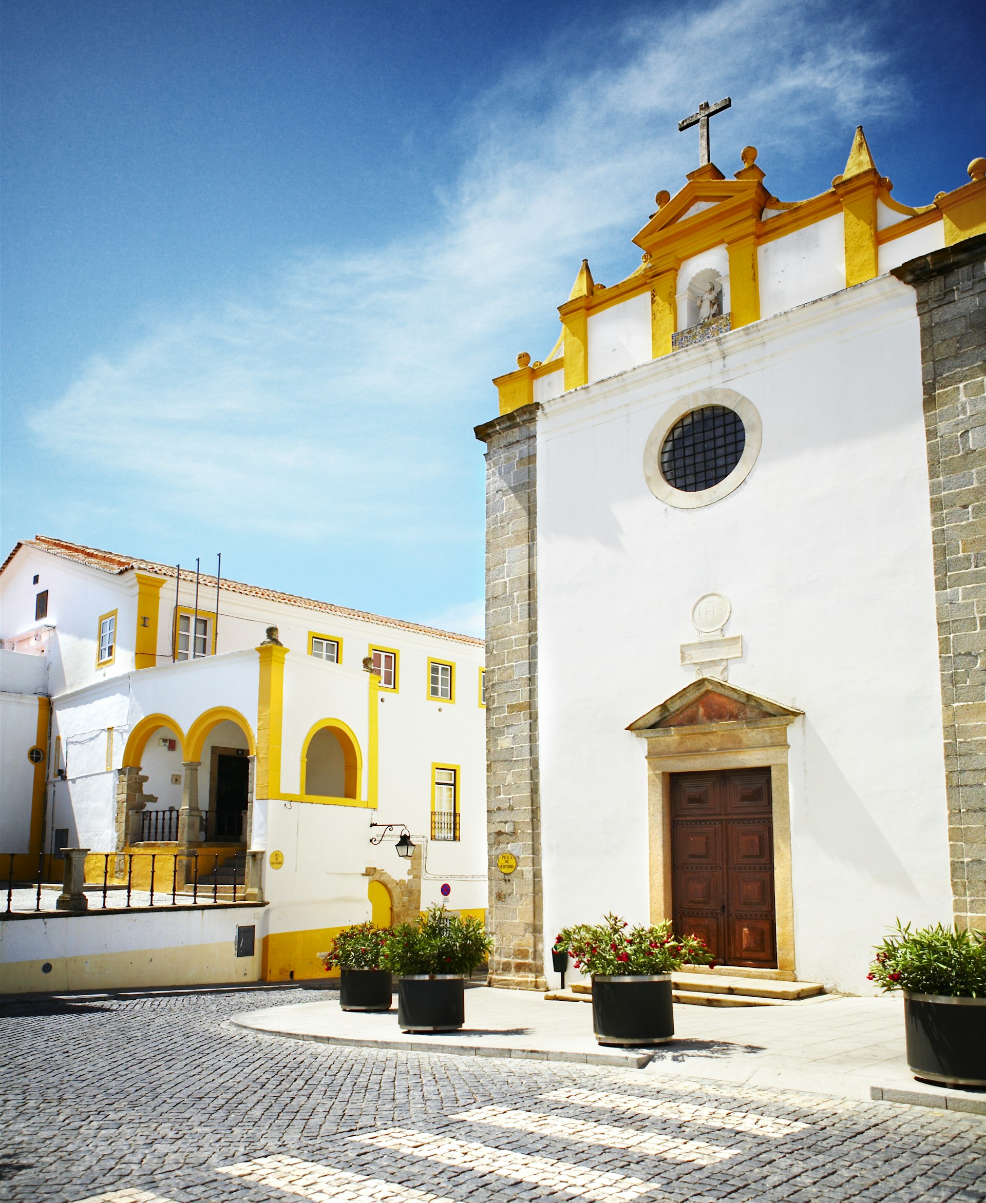 The sun shines on the white and yellow buildings of a Portuguese town. 