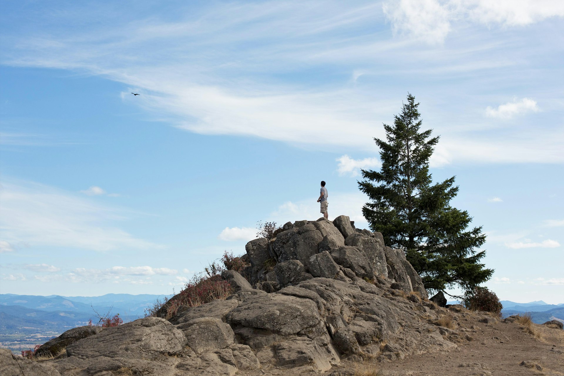 A young man standing on top of rocks, on top of Spencer Butte in Eugene, Oregon, USA.