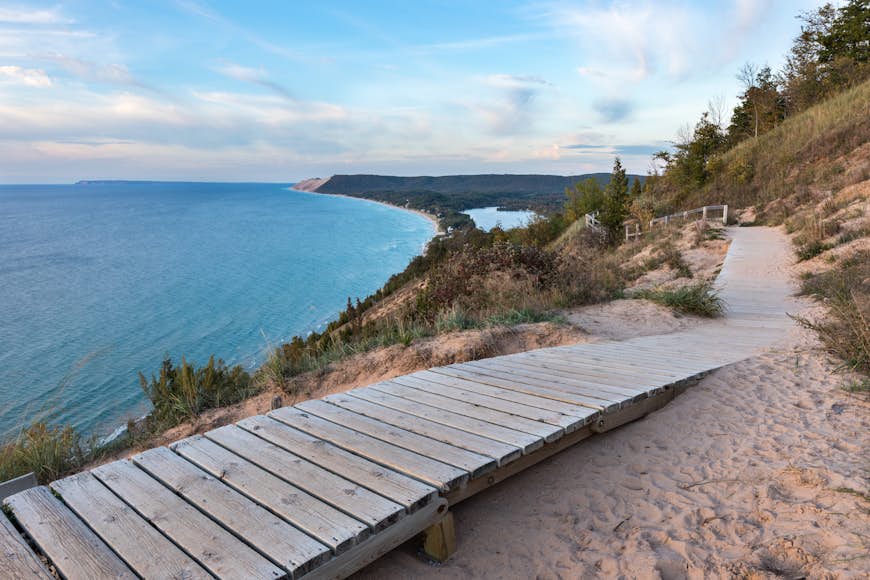 A boardwalk in Sleeping Bear Dunes National Lakeshore runs along a section of coast with the blue water of Lake Michigan beyond