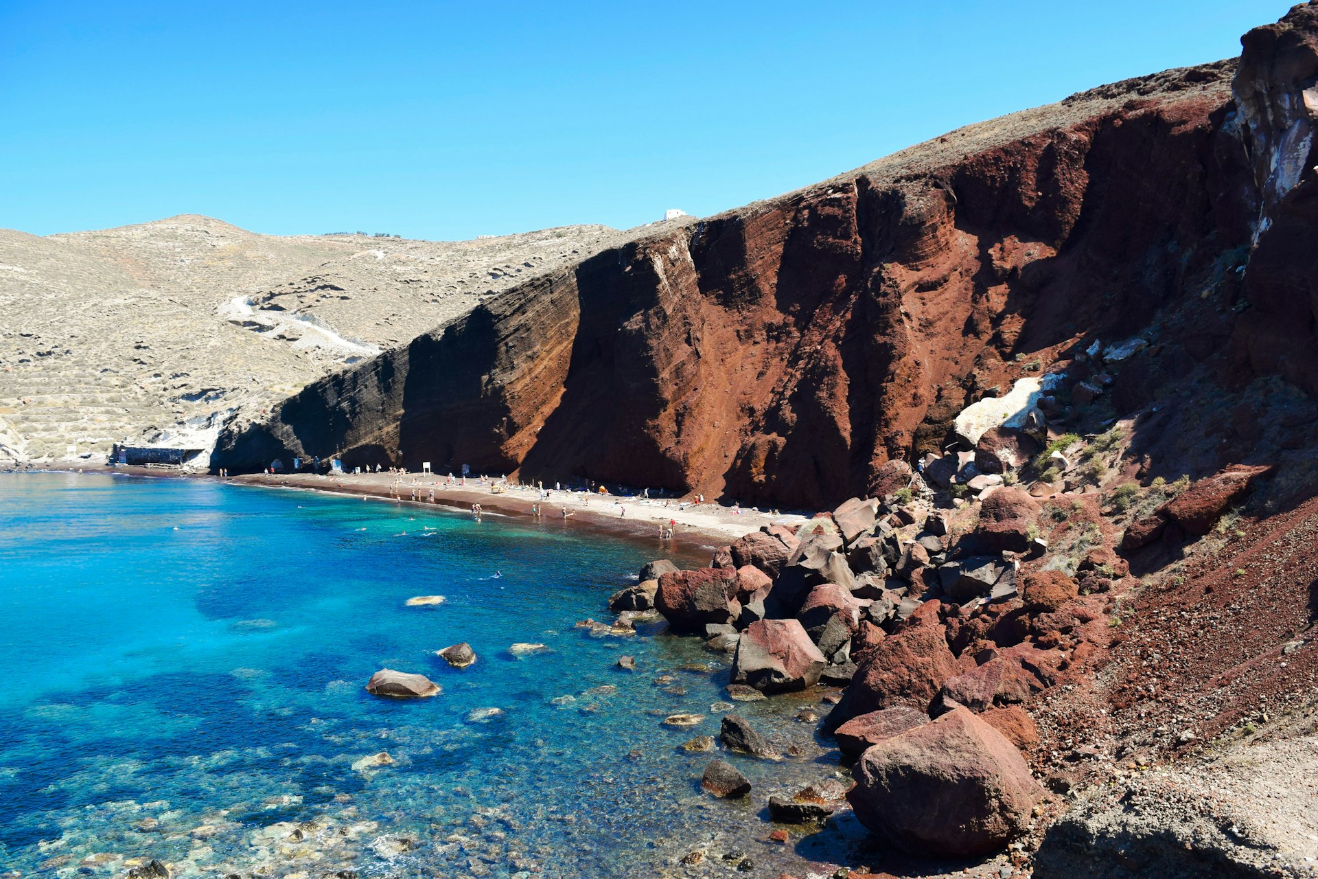 A wide-angled view of Red Beach on the island of Santorini in Greece, which gets its name from the red-coloured cliffs visible behind the thin strip of golden sand.