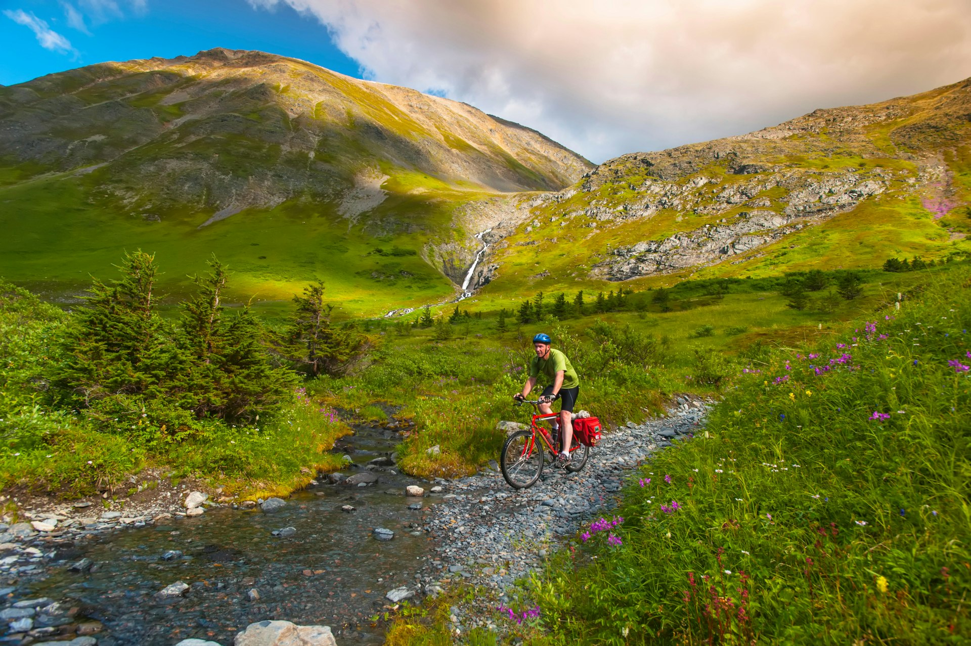 A man riding his mountain bike on the Palmer Valley Road near Hope, Alaska on a sunny summer day in South-central Alaska