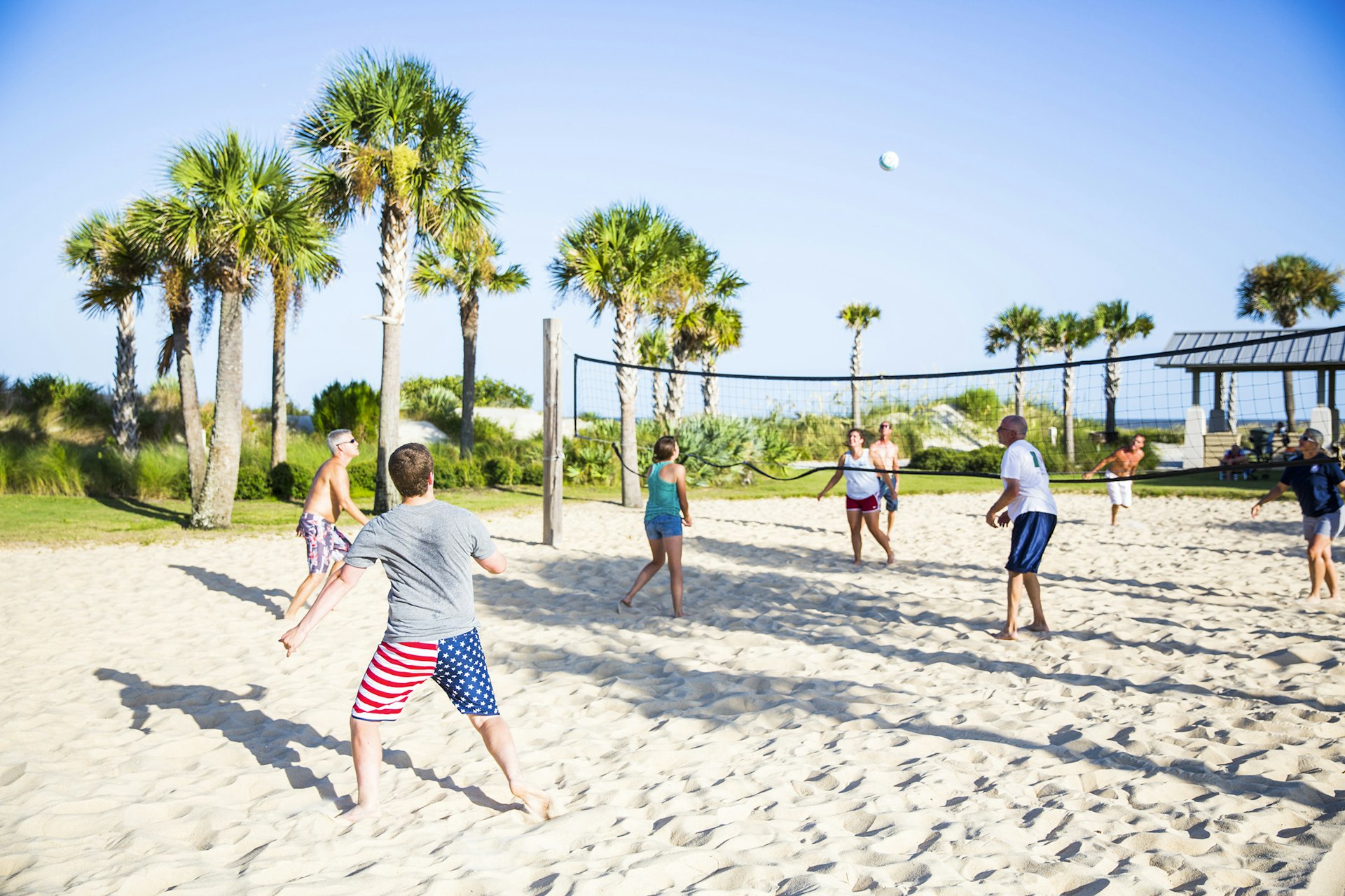 A group of people playing beach volleyball at a beach resort