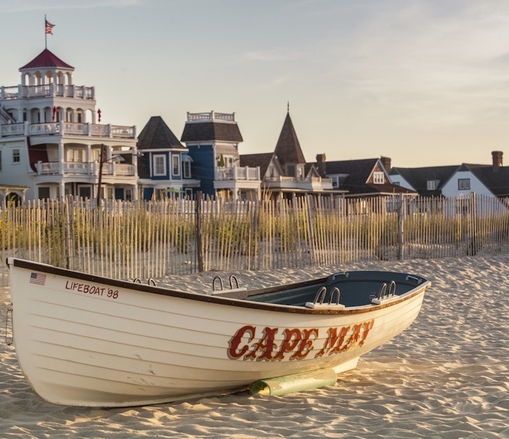 Victorian Homes and hotels line Beach Ave. in Cape May with lifesaving rescue boat on the beach.