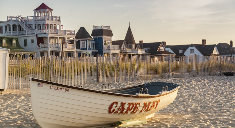 Victorian Homes and hotels line Beach Ave. in Cape May with lifesaving rescue boat on the beach.