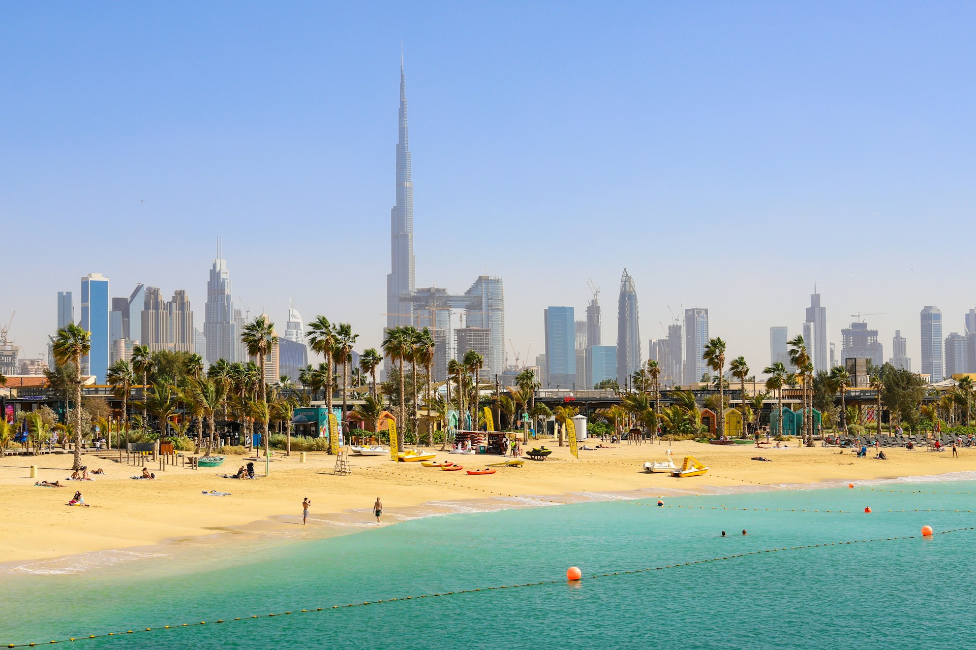 People at La Mer Beach with skyscrapers of Dubai in the background