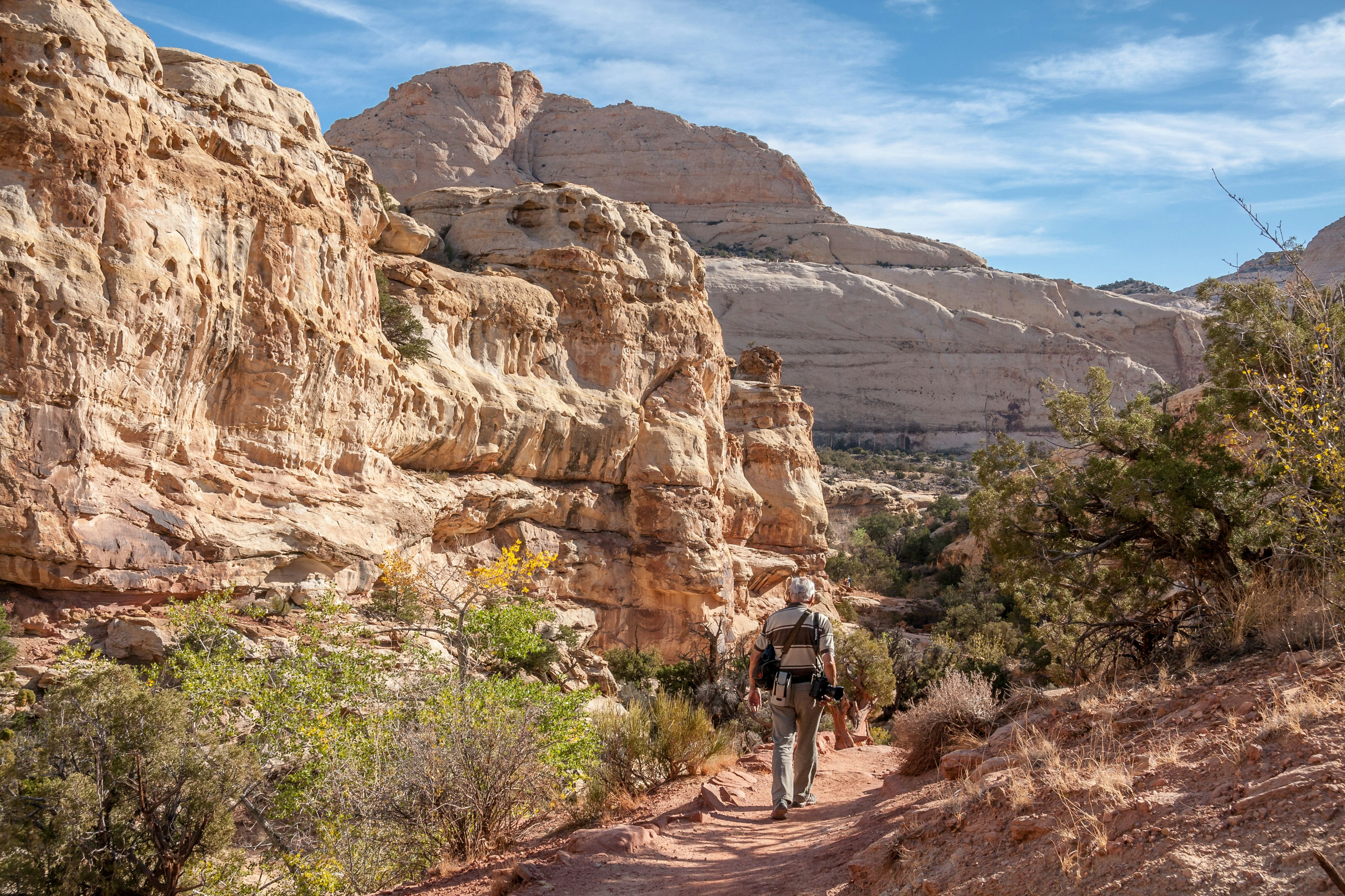 A photographer walking down a rocky path, with rock formations in the background