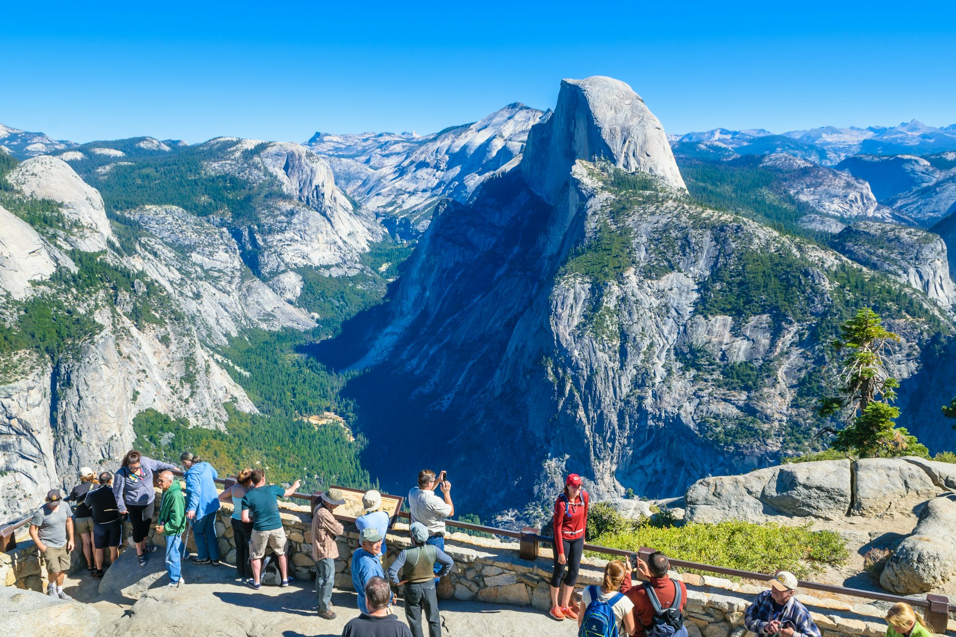 Visitors gather at Glacier Point with the Half Dome mountain in the background. 