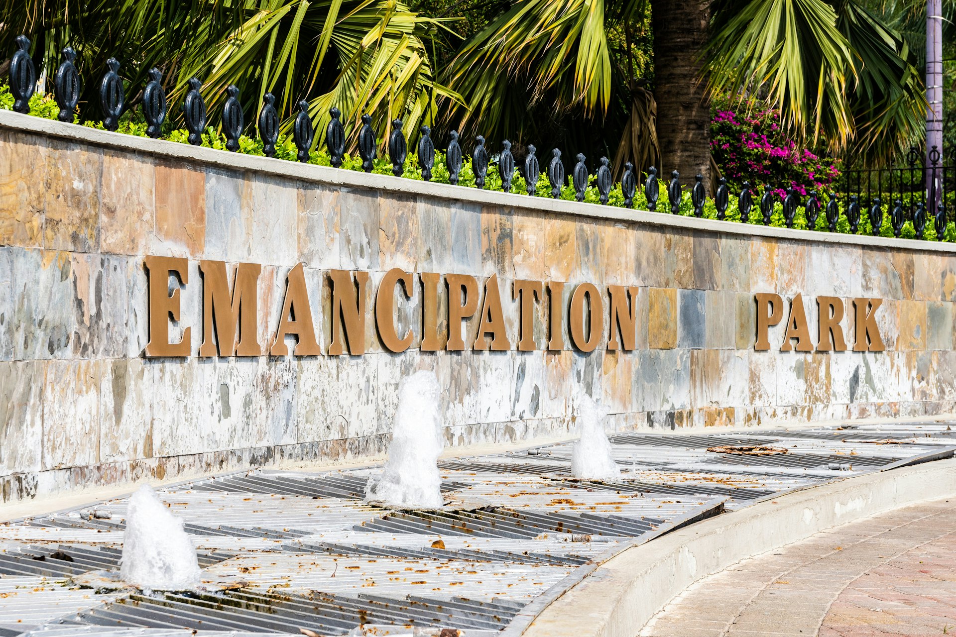 Photo of a stone wall with the words Emancipation Park in gold letters hanging off and in front of a foundation