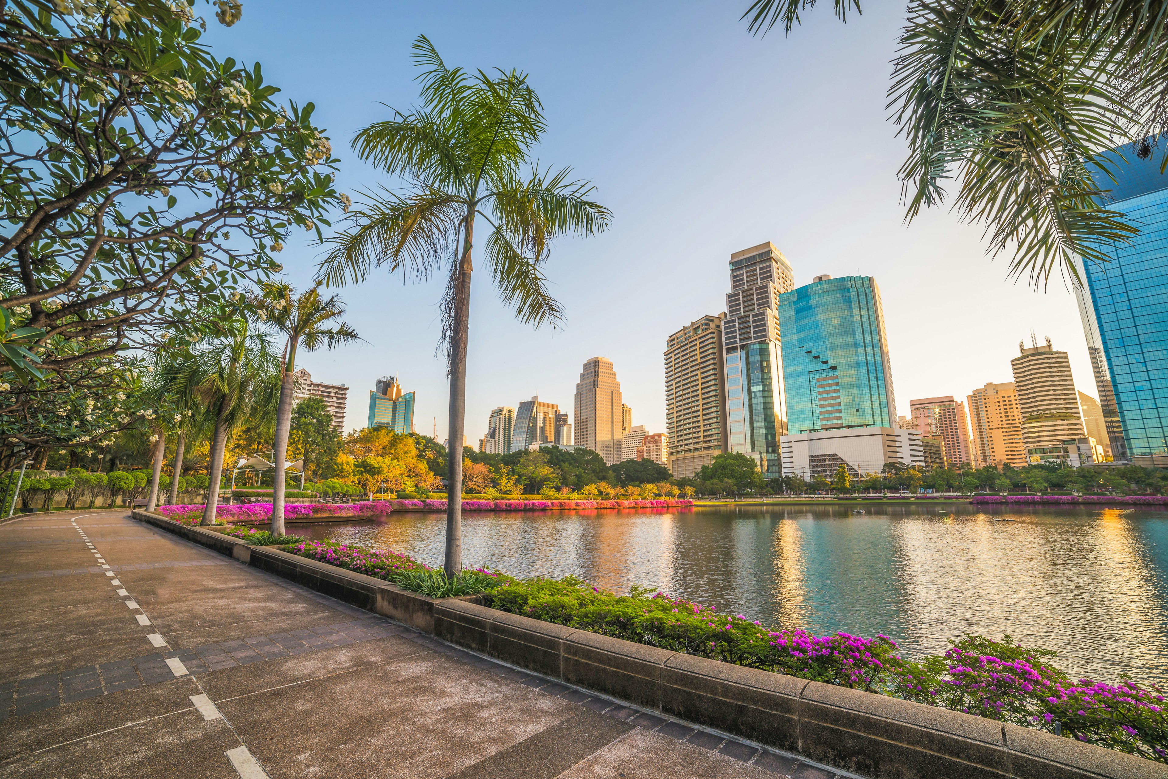 Empty running track in Benjakiti Park, Bangkok at sunrise with skyscrapers in the background.