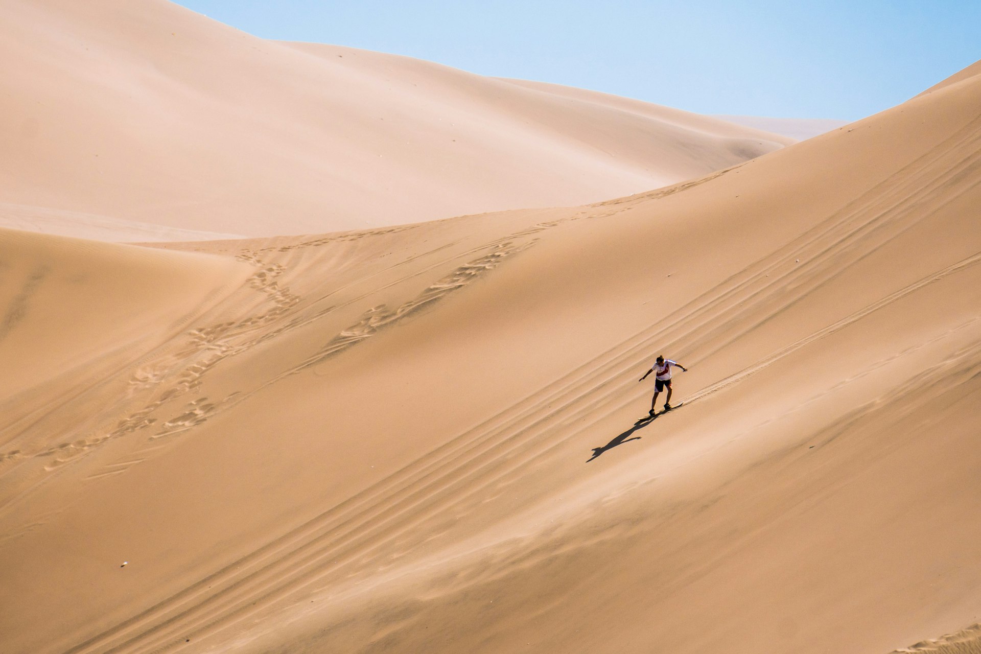 Silhouette of a man sandboarding in the desert. 