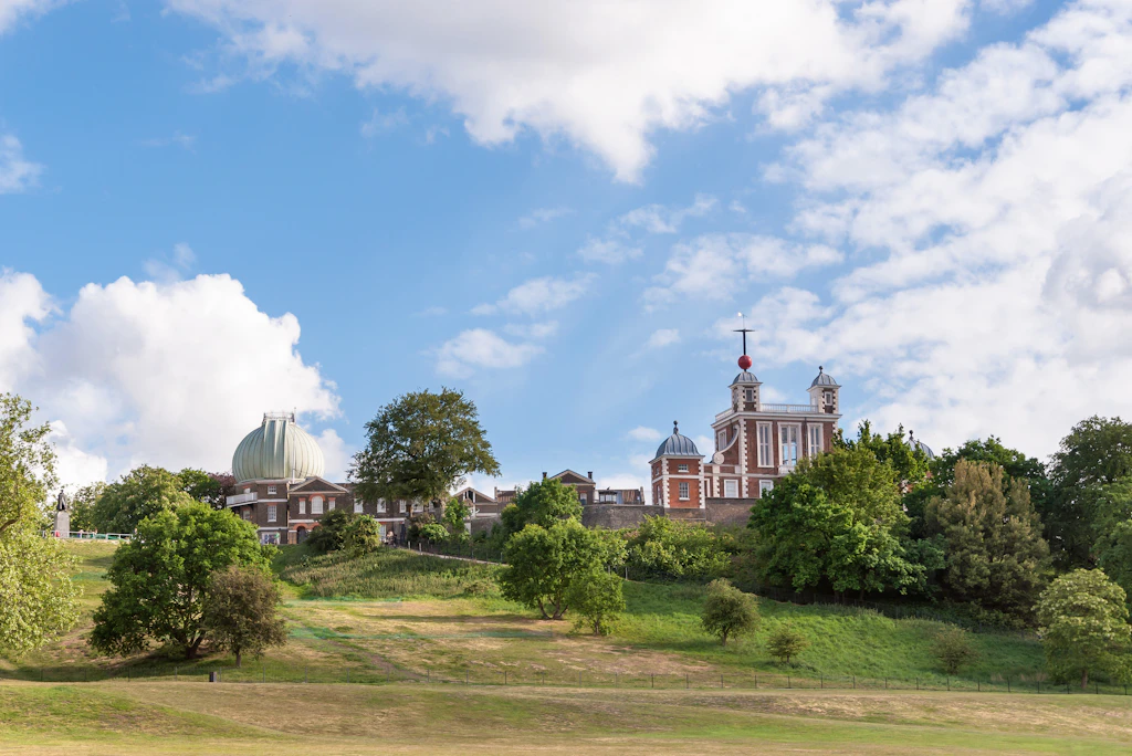 A large expanse of green with a red-brick observatory building at the top of a hill