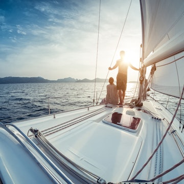 Young couple looking to the sunset on the yacht in Andaman sea near Thailand.