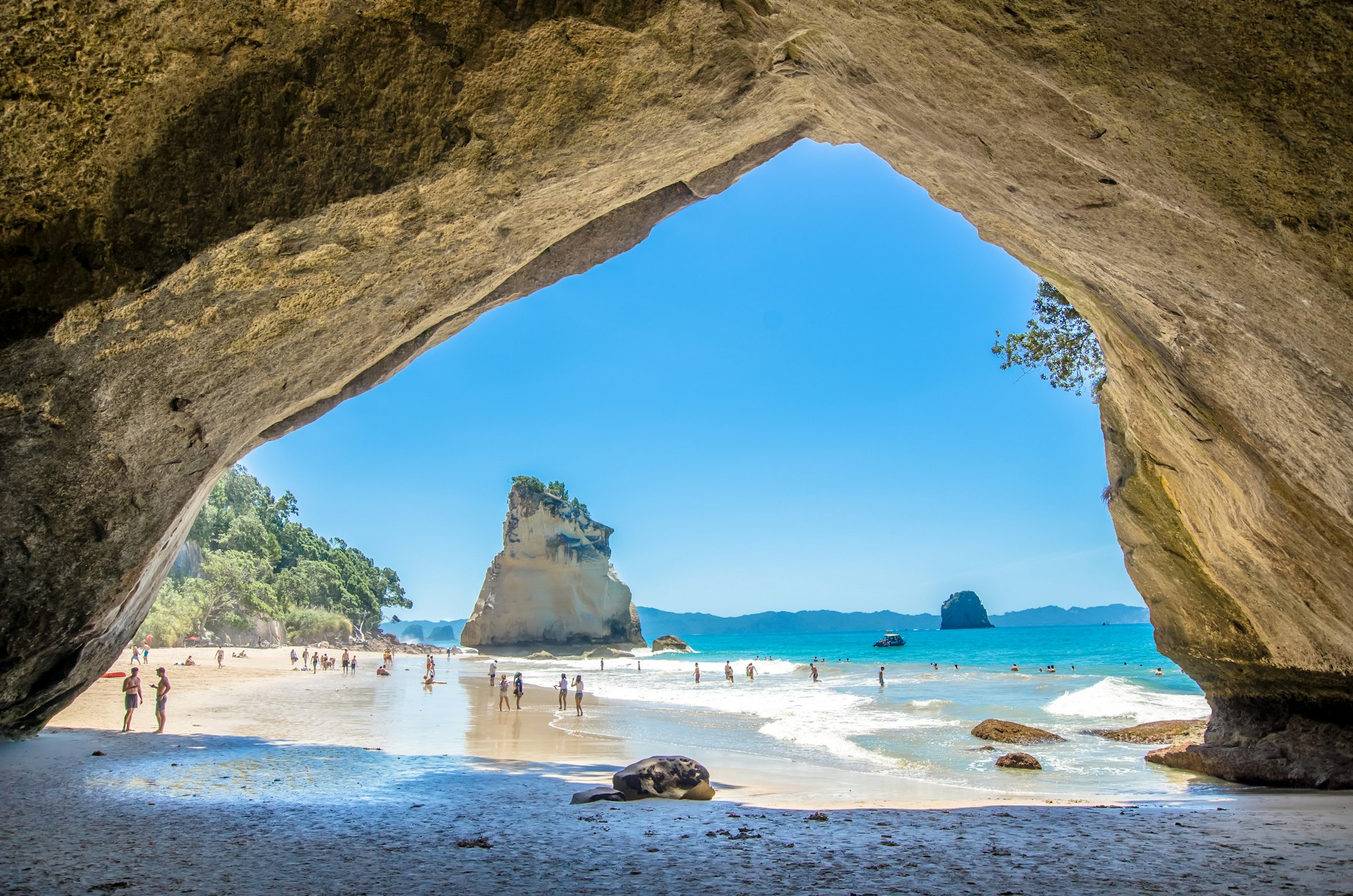 The beach at Cathedral Cove as photographed through the stone arch. It's a busy sunny day with lots of people on the beach