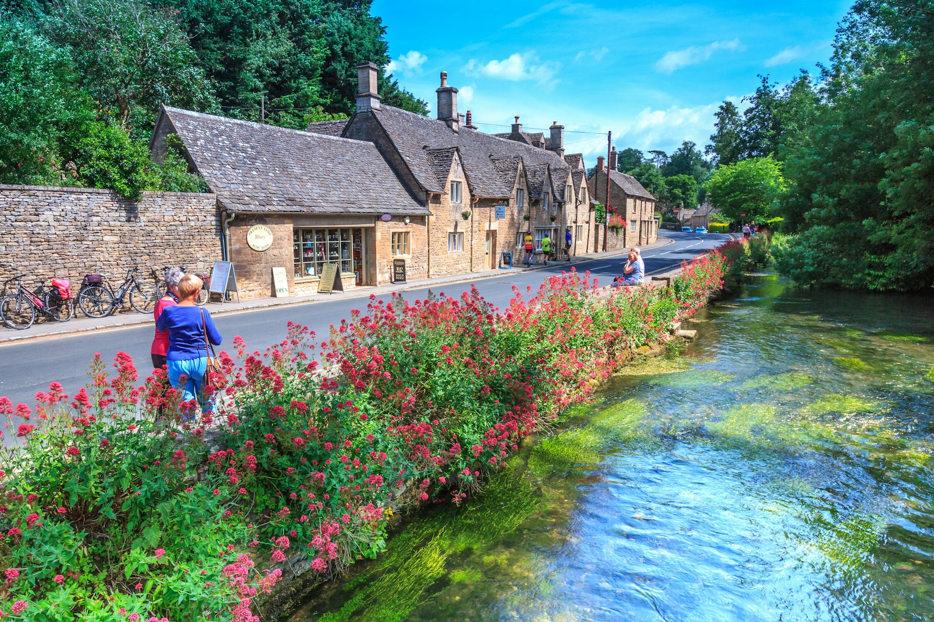 Traditional Cotswold stone cottages line a street in a quaint English village