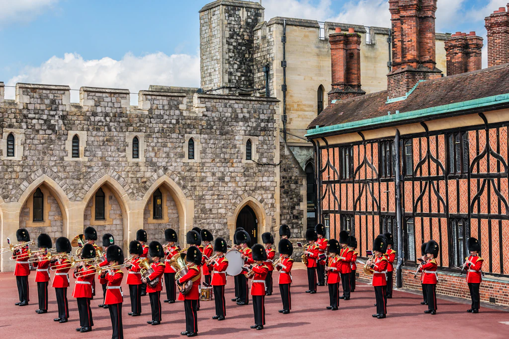 Changing of the Guard, Windsor Castle Rows of guards in red-and-black uniforms play musical instruments in a castle courtyard
