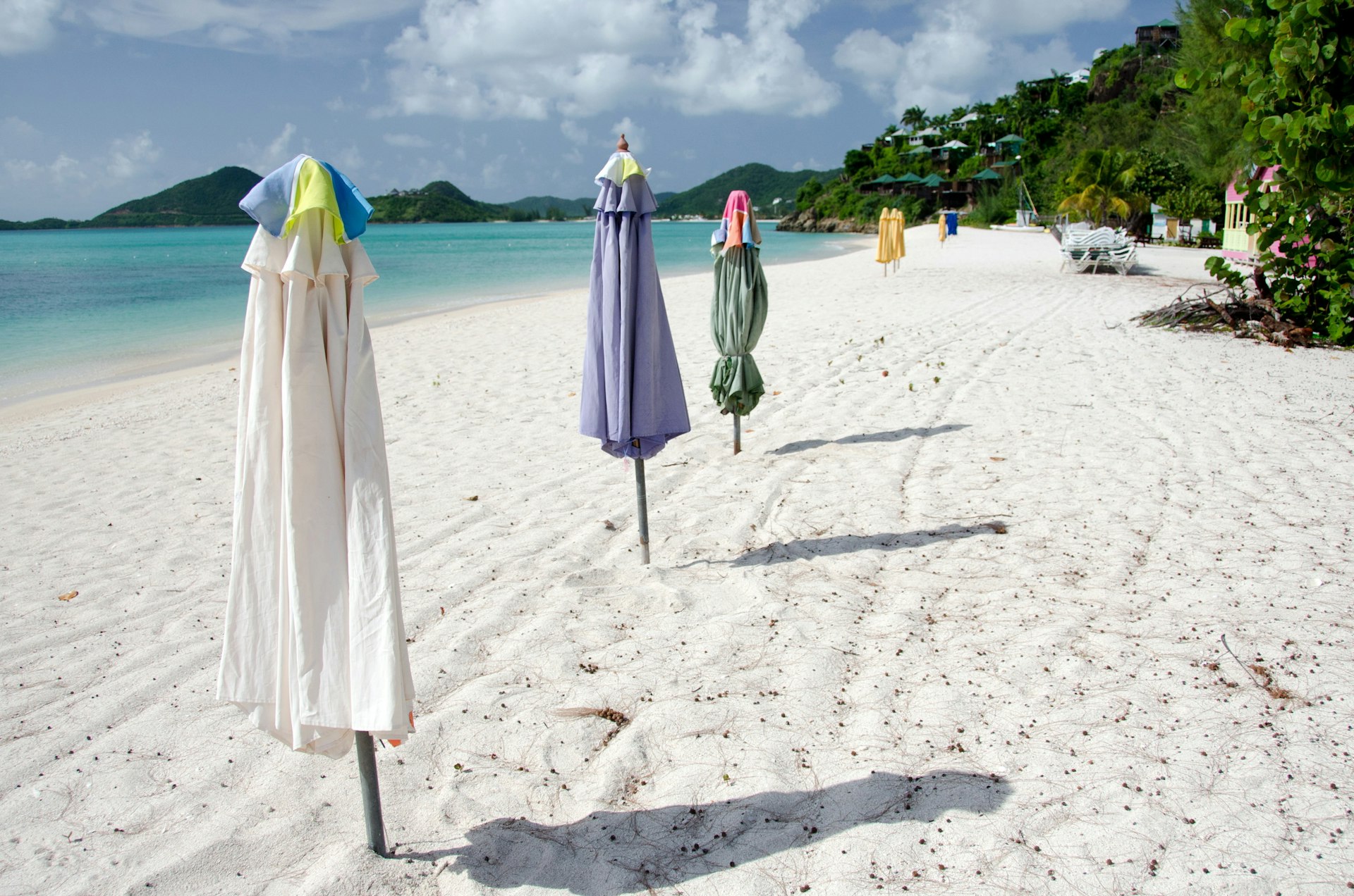 Row of beach umbrellas crosses white sands of Church Valley beach