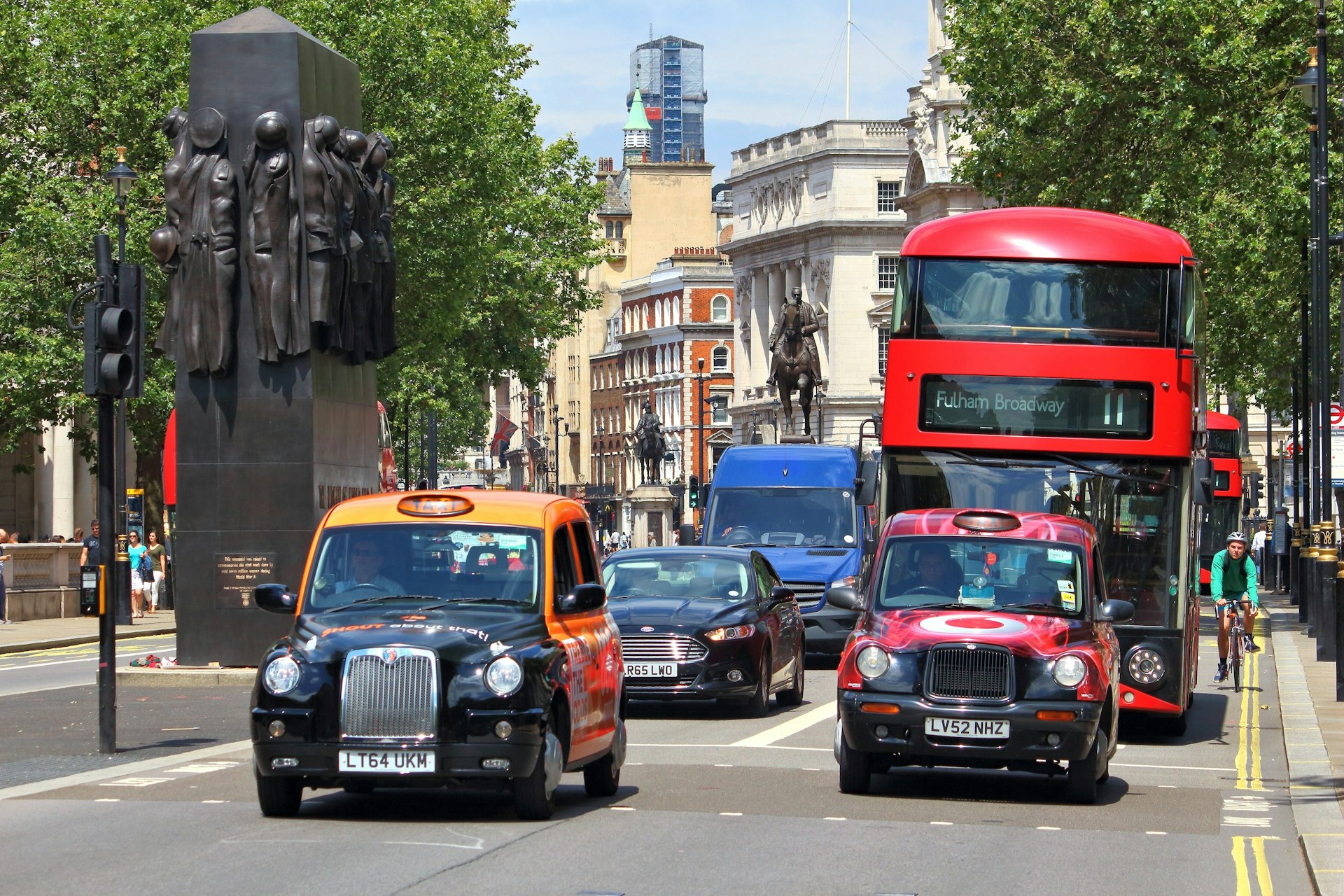 London's iconic black cabs wait at lights in front of a double-decker red bus