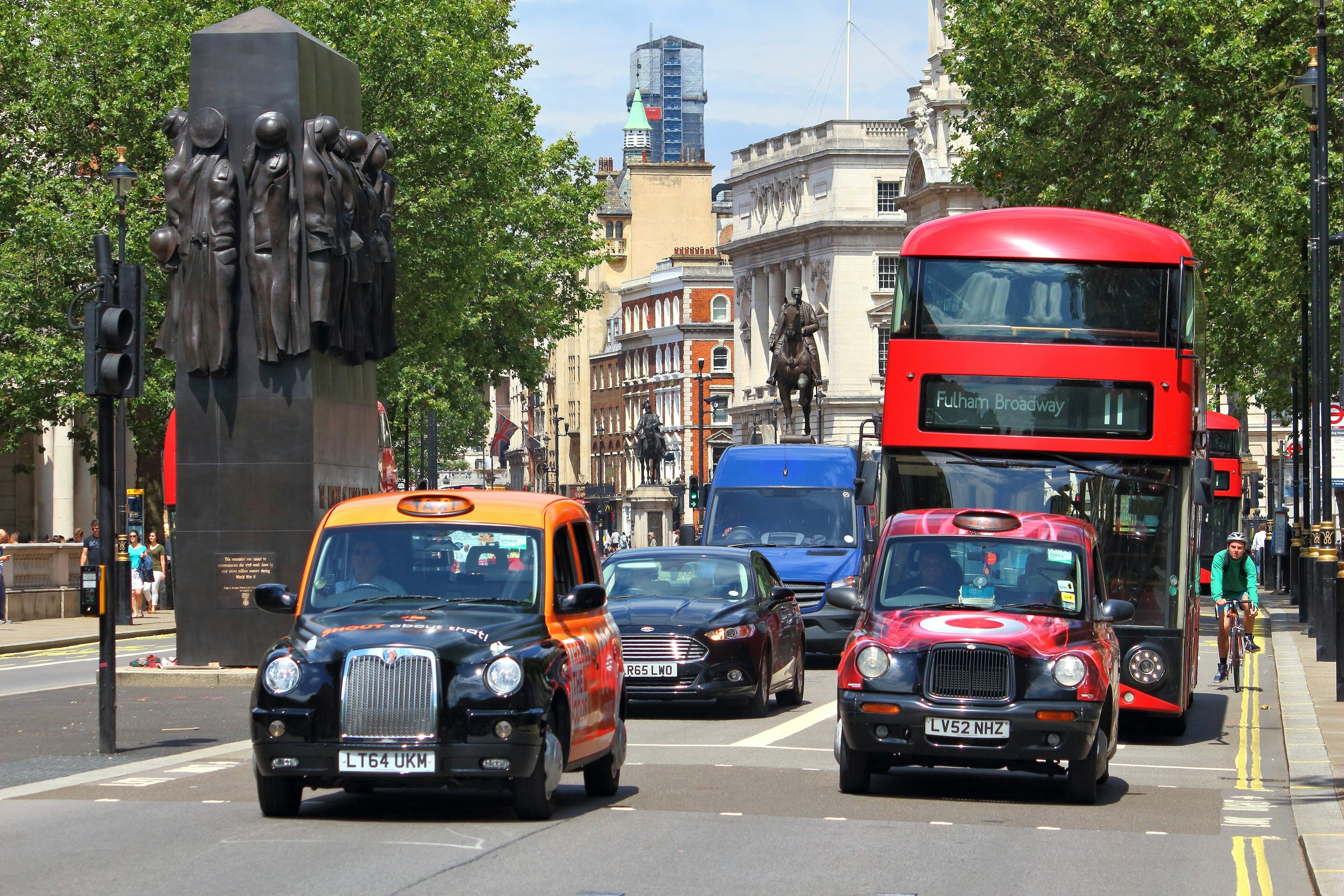 London's iconic black cabs wait at lights in front of a double-decker red bus