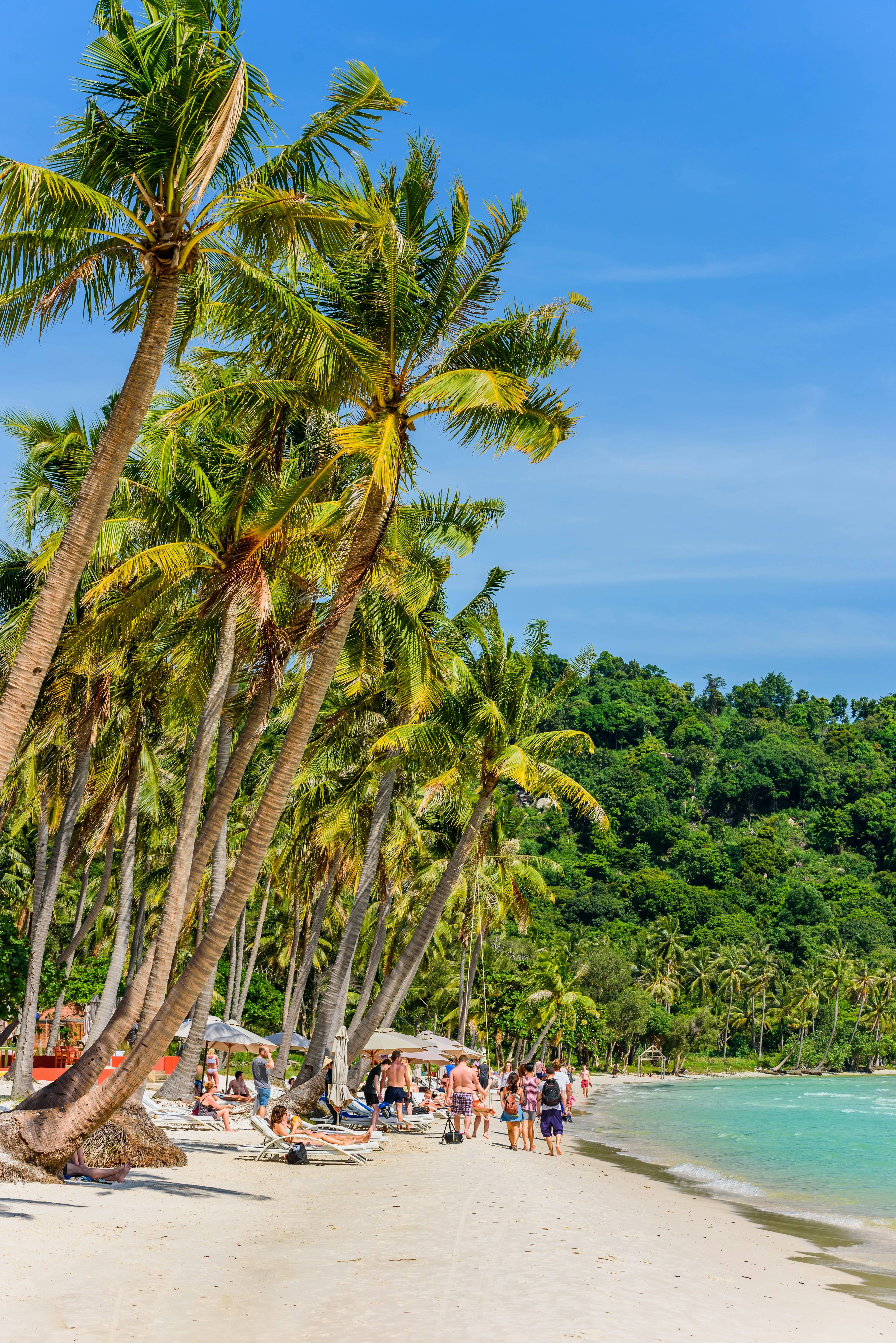 Beach goers on the white sandy Sao beach with palms