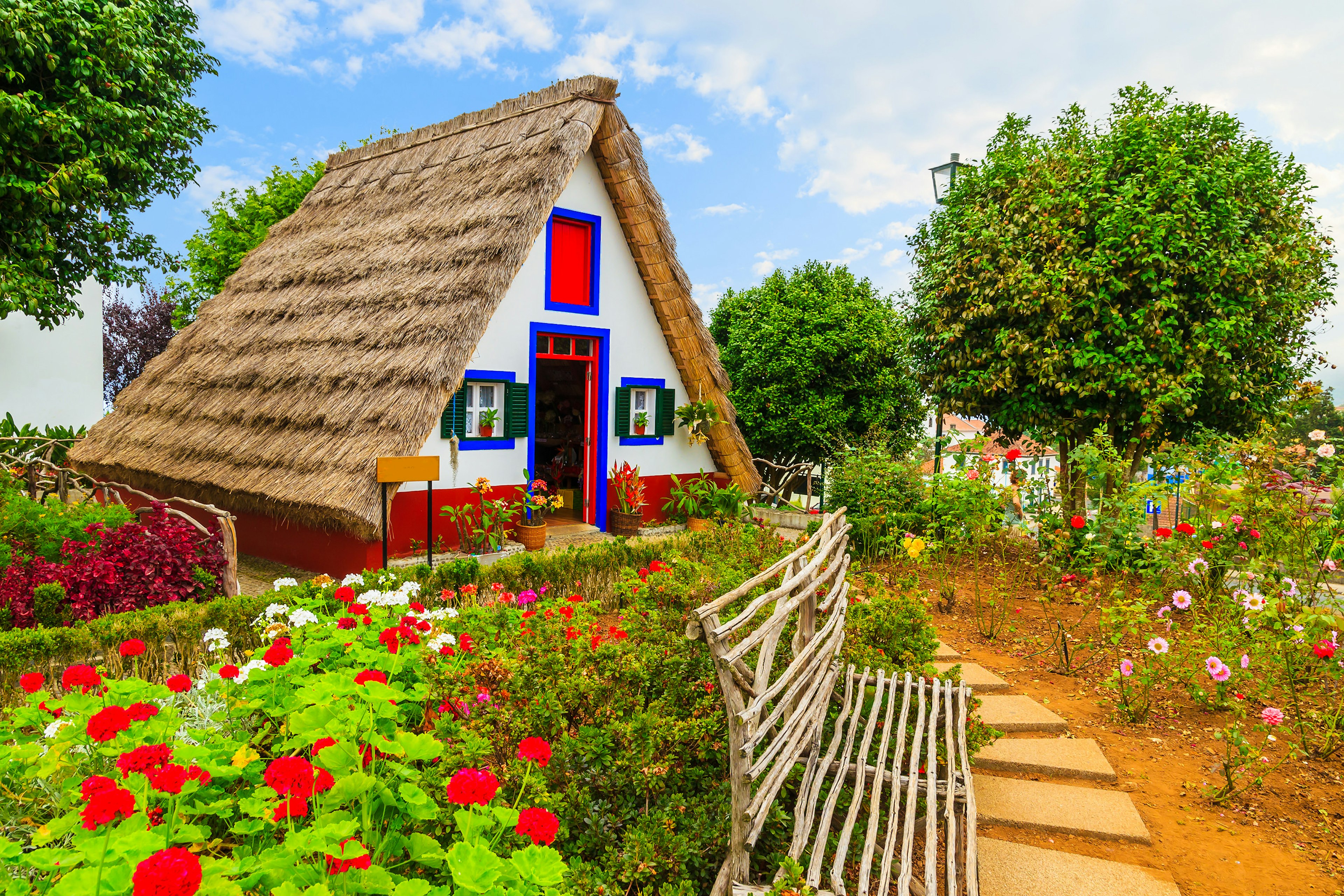 A traditional rural home with red and blue window trim and a garden in front.