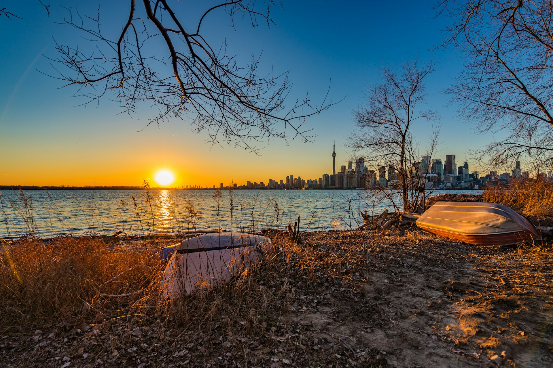 A sunset with a city skyline in the background, boats in the foreground