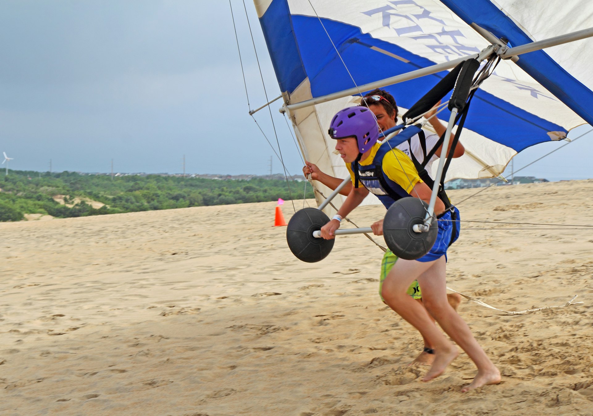 A person prepares for takeoff in a hang glider over a beach