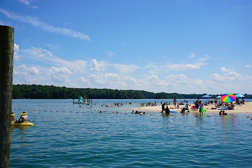 Swimmers enjoy a lake beach under blue skies