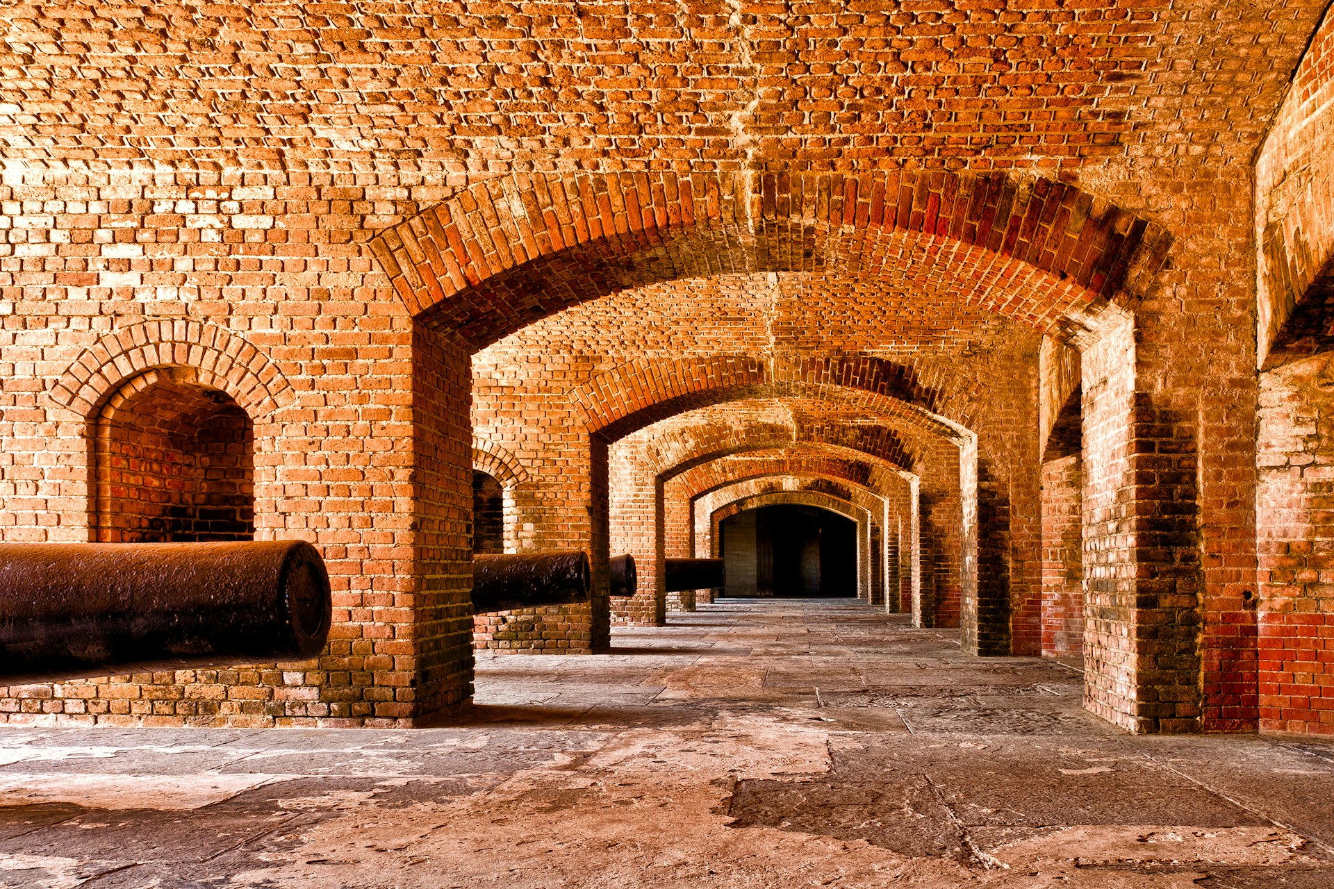 Rows of cannons under a brick fortress 