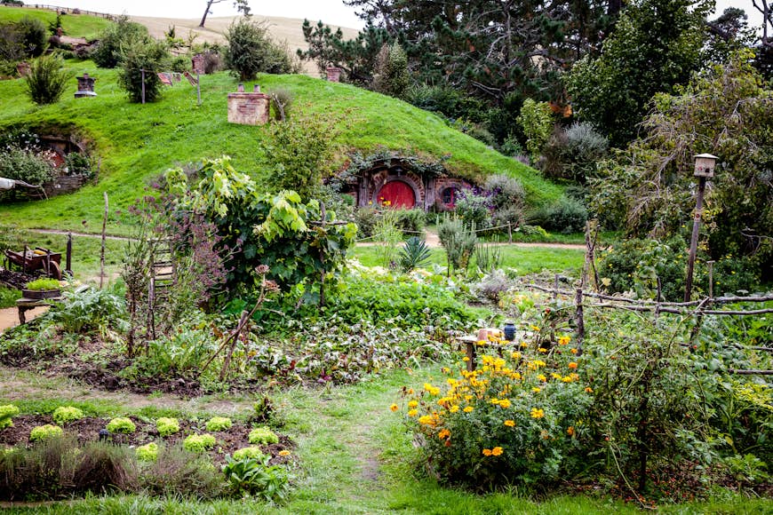 A small hobbit house is built into a green hill in Hobbiton in Matamata, New Zealand 