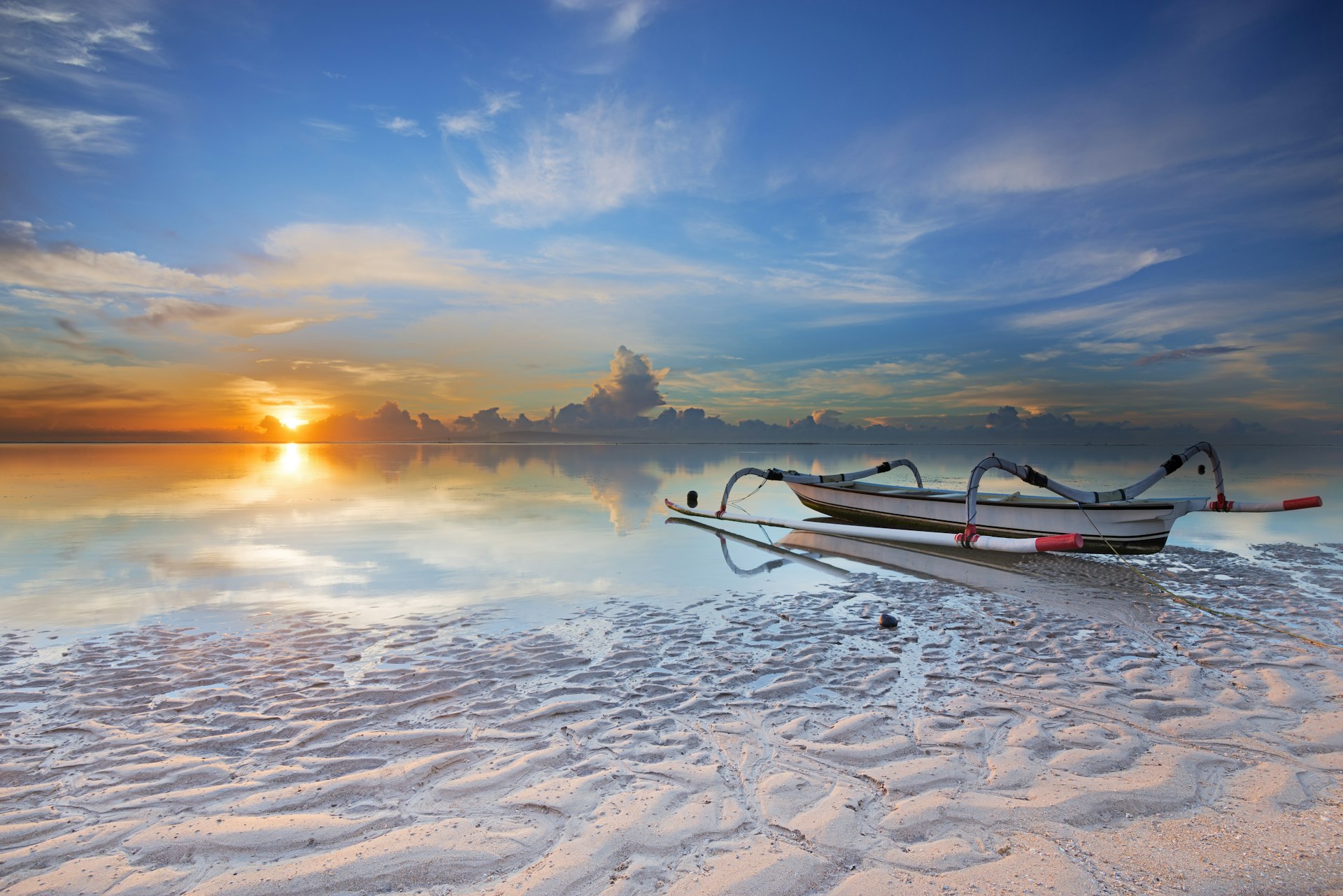 Boat on the white sands of Sanur Beach at sunrise in Bali, Indonesia
