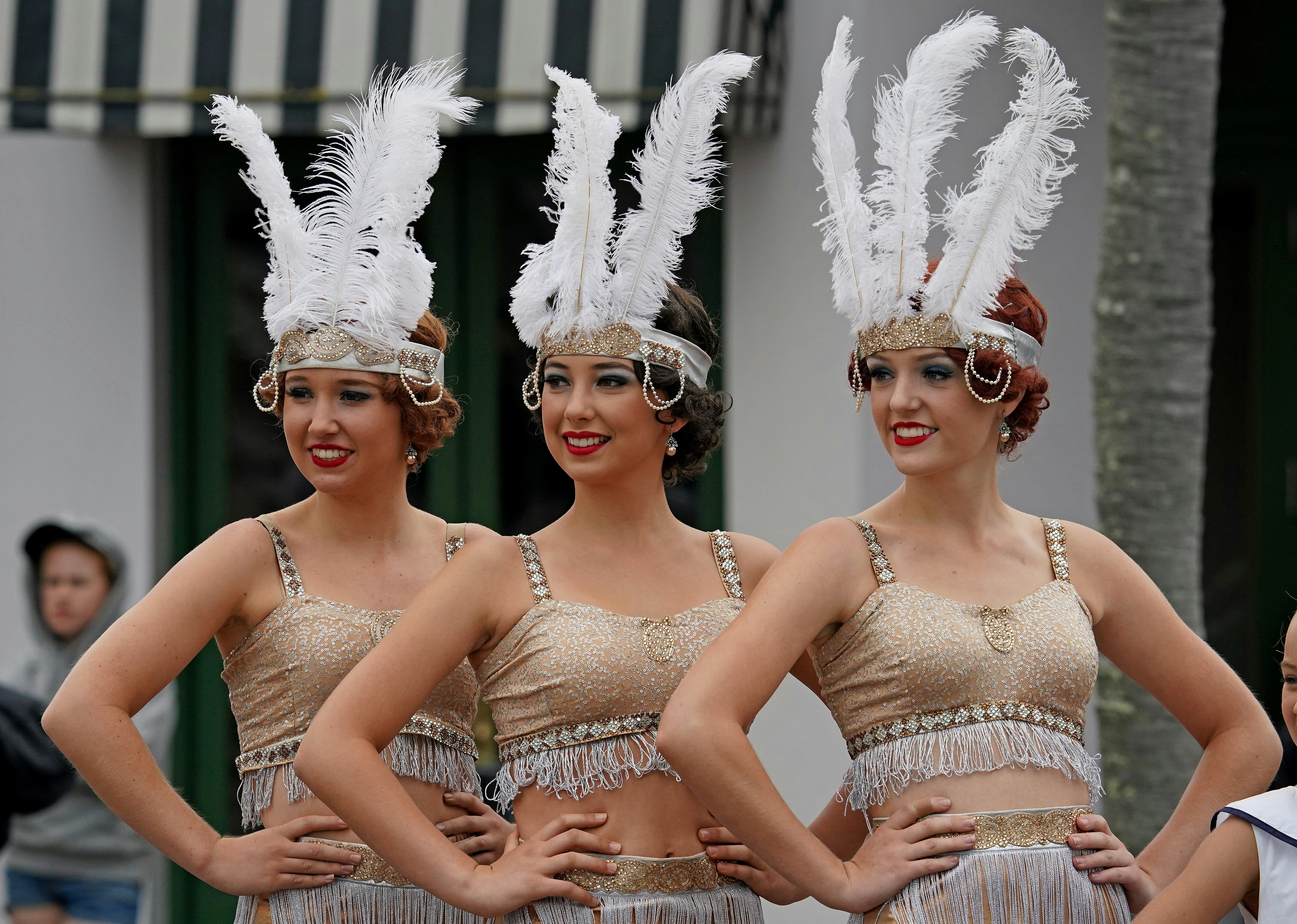 Ladies dressed as 1920s showgirls pose wearing white feather headbands and sparkly tops with fringe at the Napier Art Deco Festival