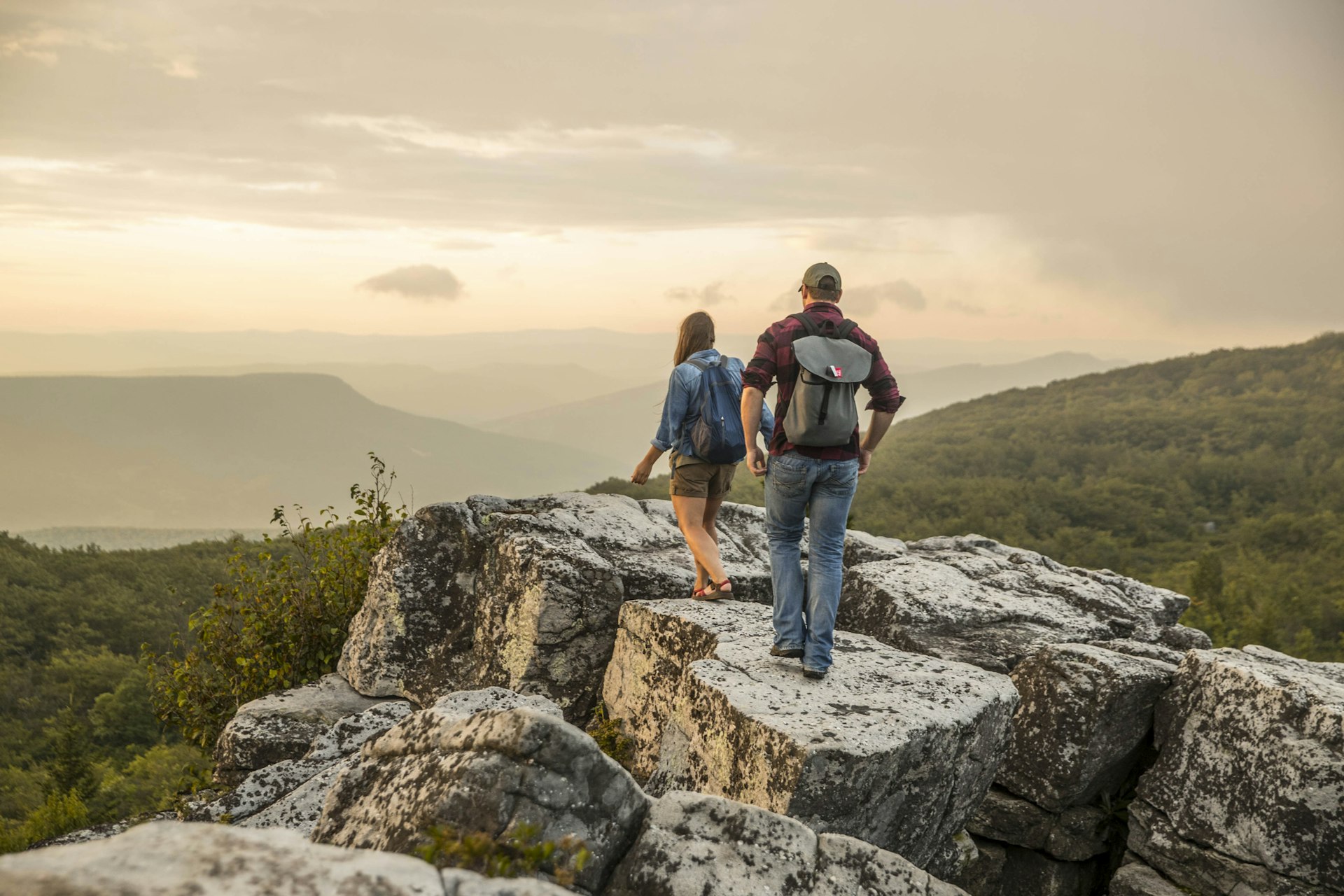 A man and woman hiking over rocks in West Virginia
