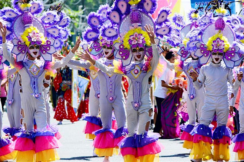 Des danseurs et des artistes parés de tenues flamboyantes et de masques souriants descendent dans les rues pour le festival Masskara aux Philippines. 