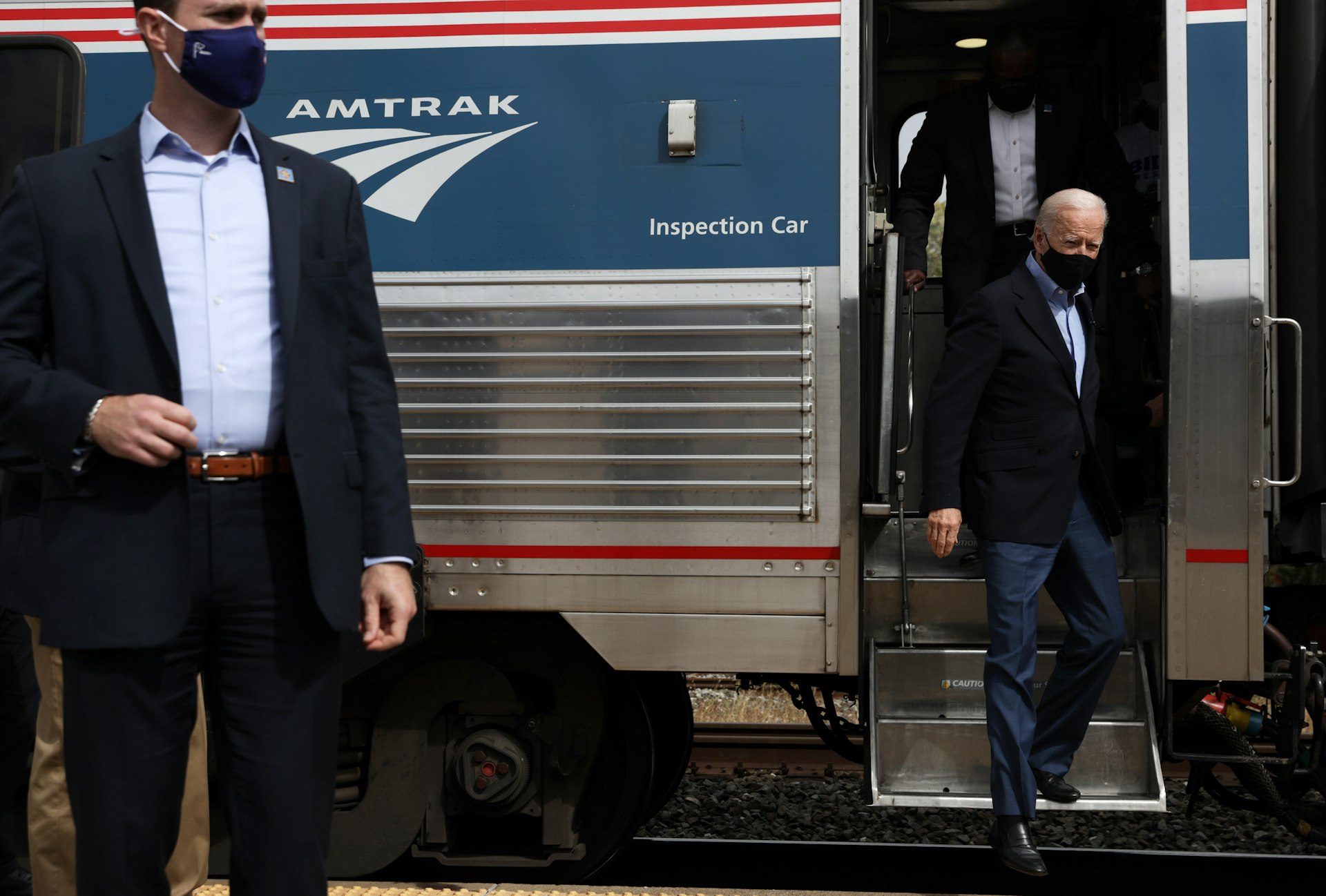 Joe Biden disembarks at a campaign stop at Alliance Amtrak Station in Alliance, Ohio. A secret service man is positioned to the right of the photo and another is disembarking the train directly behind him  