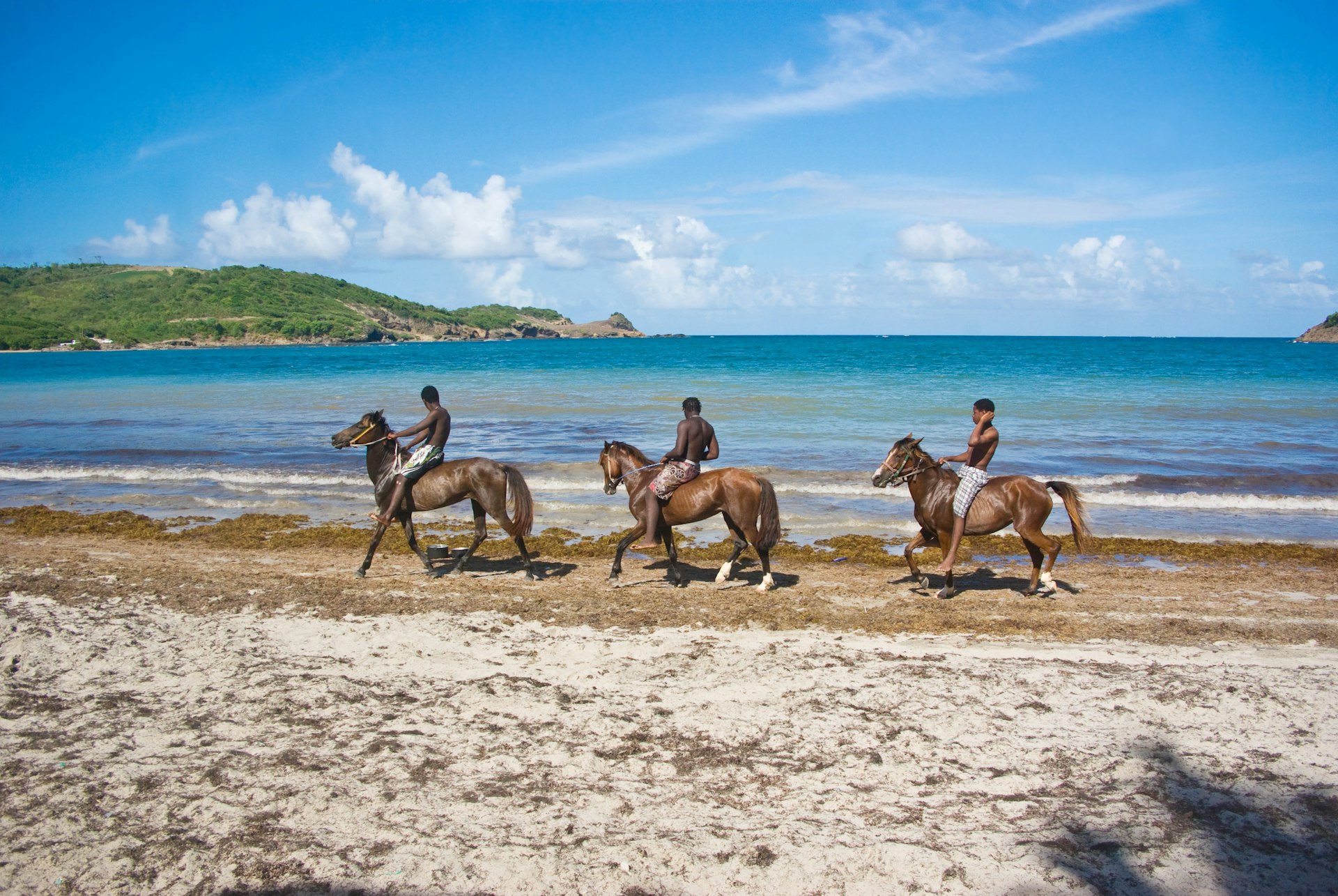 Three young men ride horses on Cas-en-Bas beach, St Lucia, West Indies, Caribbean