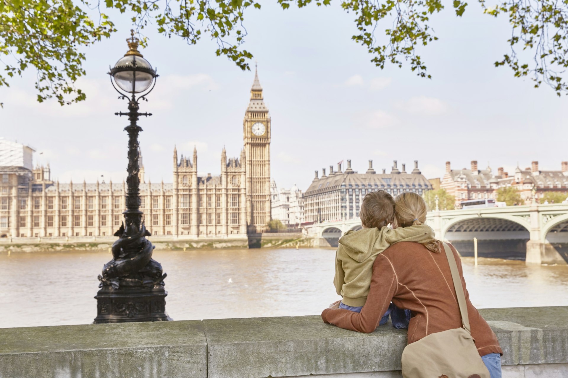 Mother and son looking over the Thames River at Big Ben and the Houses of Parliament in London
