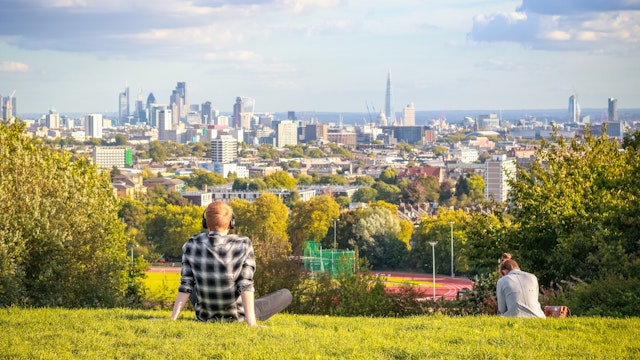 London, UK - October 5, 2017 - Back view of tourists looking over London city skyline from Hampstead Heath
