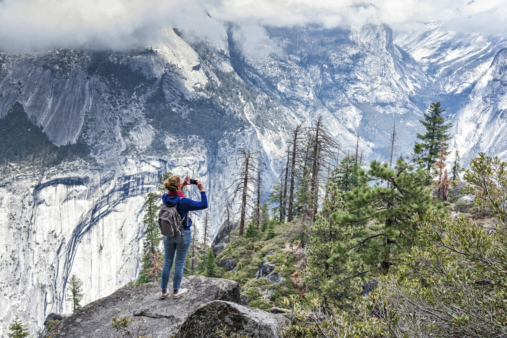 A woman wearing a backpack taking photo in Yosemite