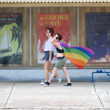 July 24, 2018: Two women walking along the sidewalk, one with a pride flag, during St. Pete Pride.