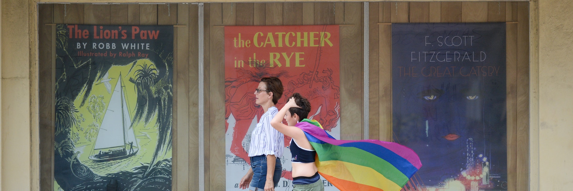 July 24, 2018: Two women walking along the sidewalk, one with a pride flag, during St. Pete Pride.