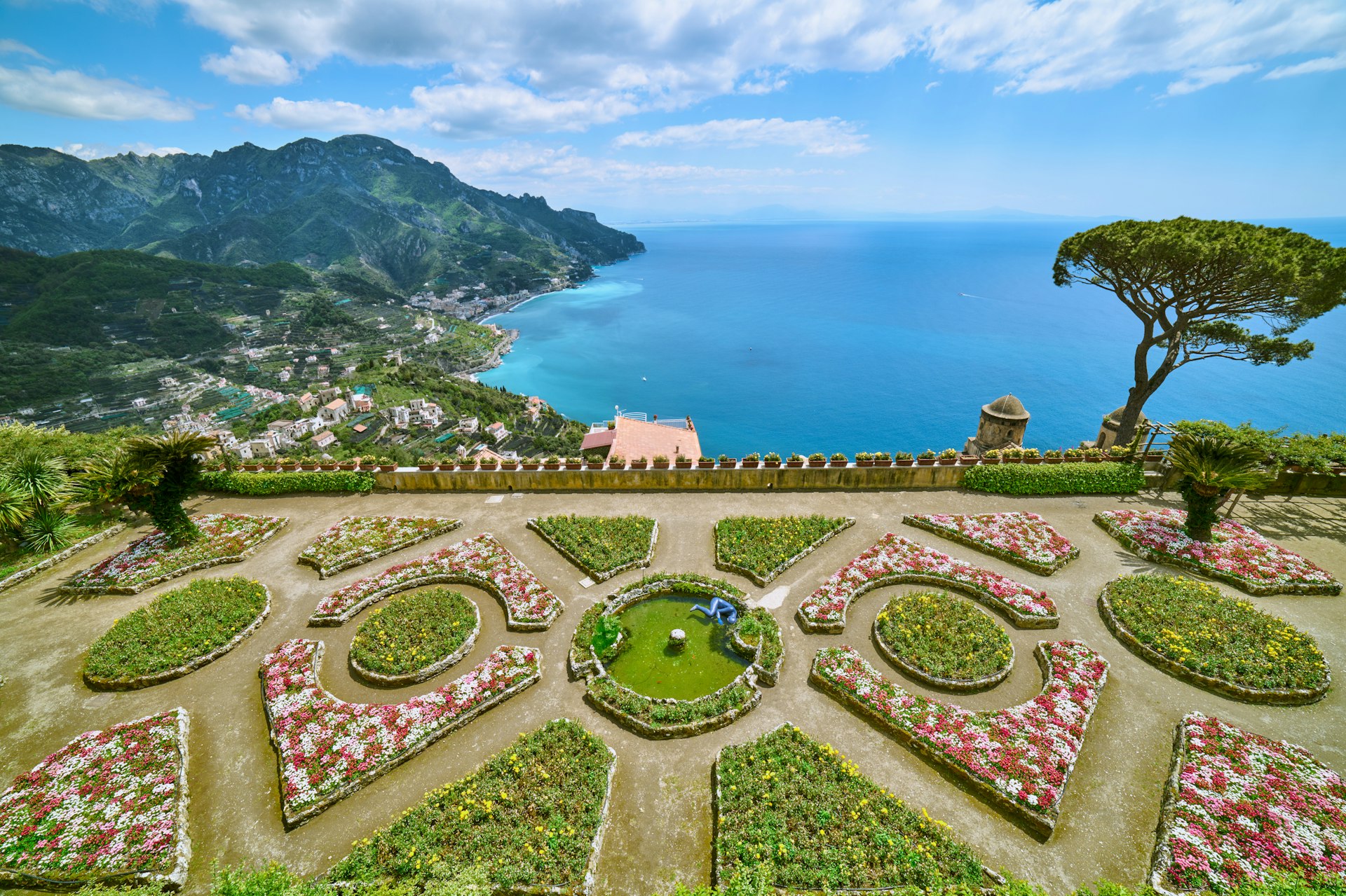 A colorful formal garden laid out with flower beds high up above a beautiful coastline