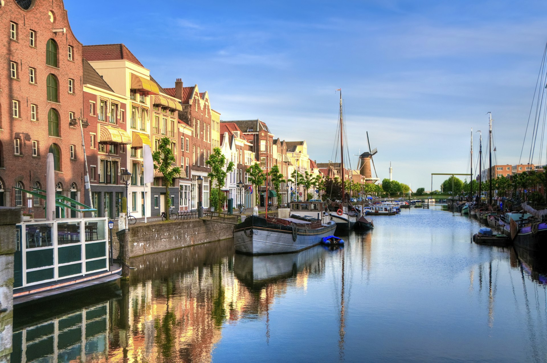 A canal lined with boats with tall masts