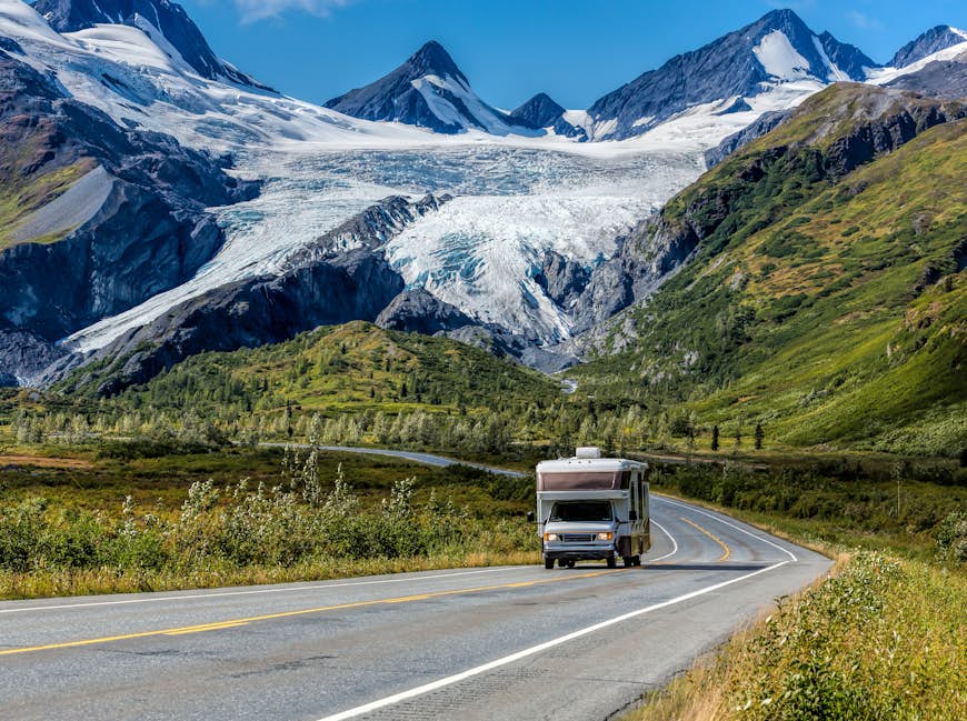 An RV driving on the Richardson Highway in Alaska with a glacier and mountains in the background