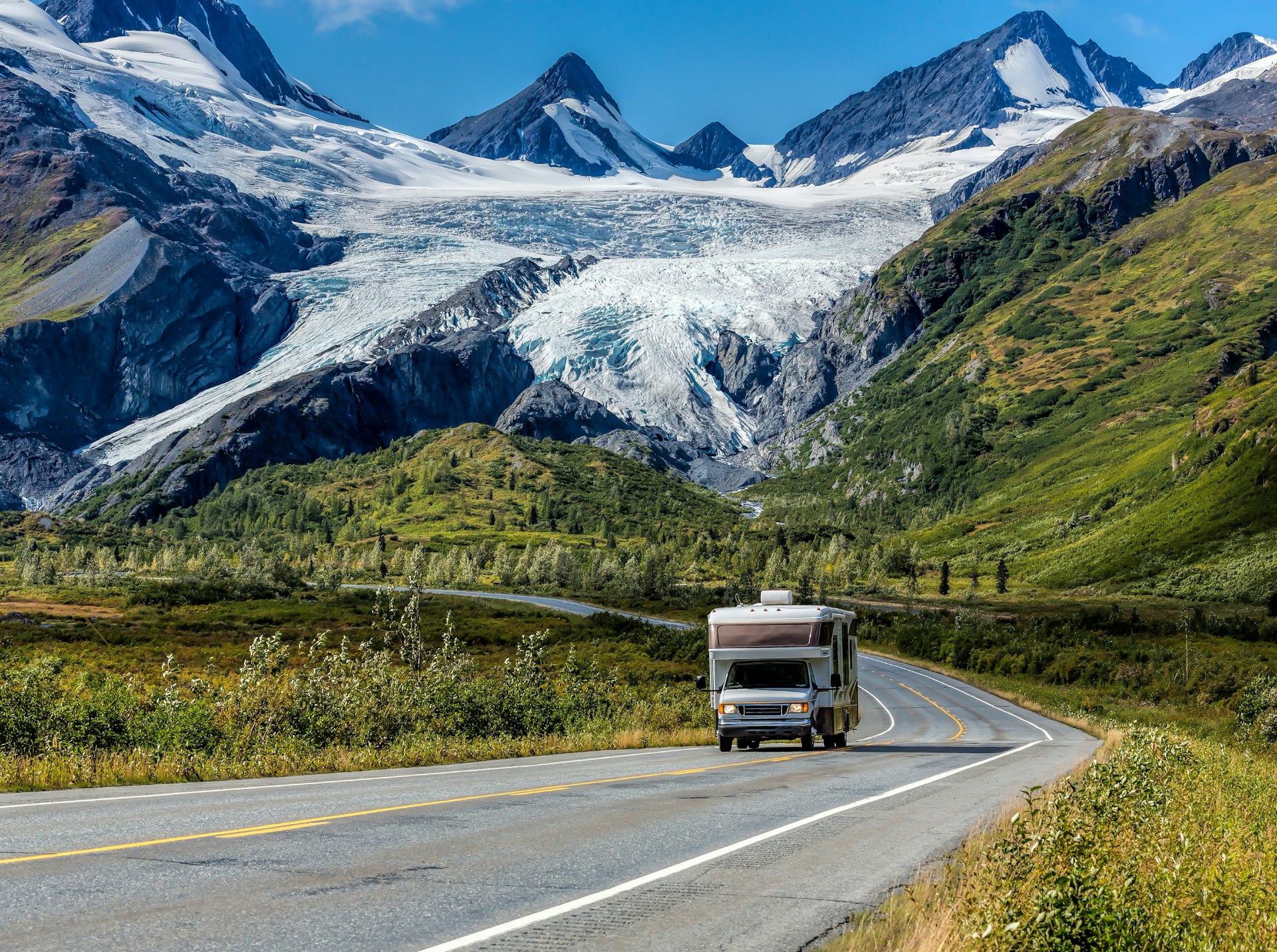 An RV driving on the Richardson Highway in Alaska with a glacier and mountains in the background