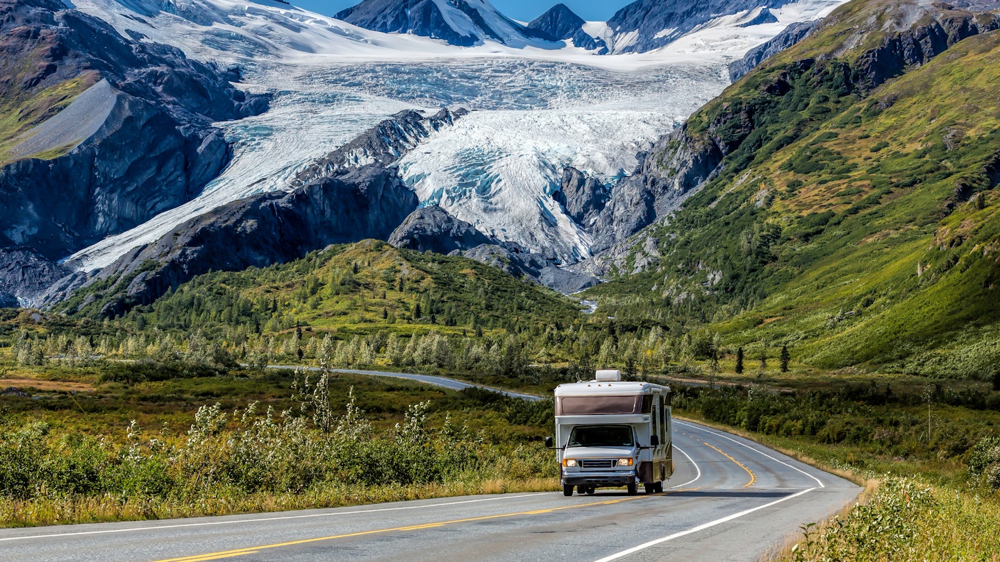 An RV travels along the Richardson Highway in Alaska, with the Worthington Glacier in the background.