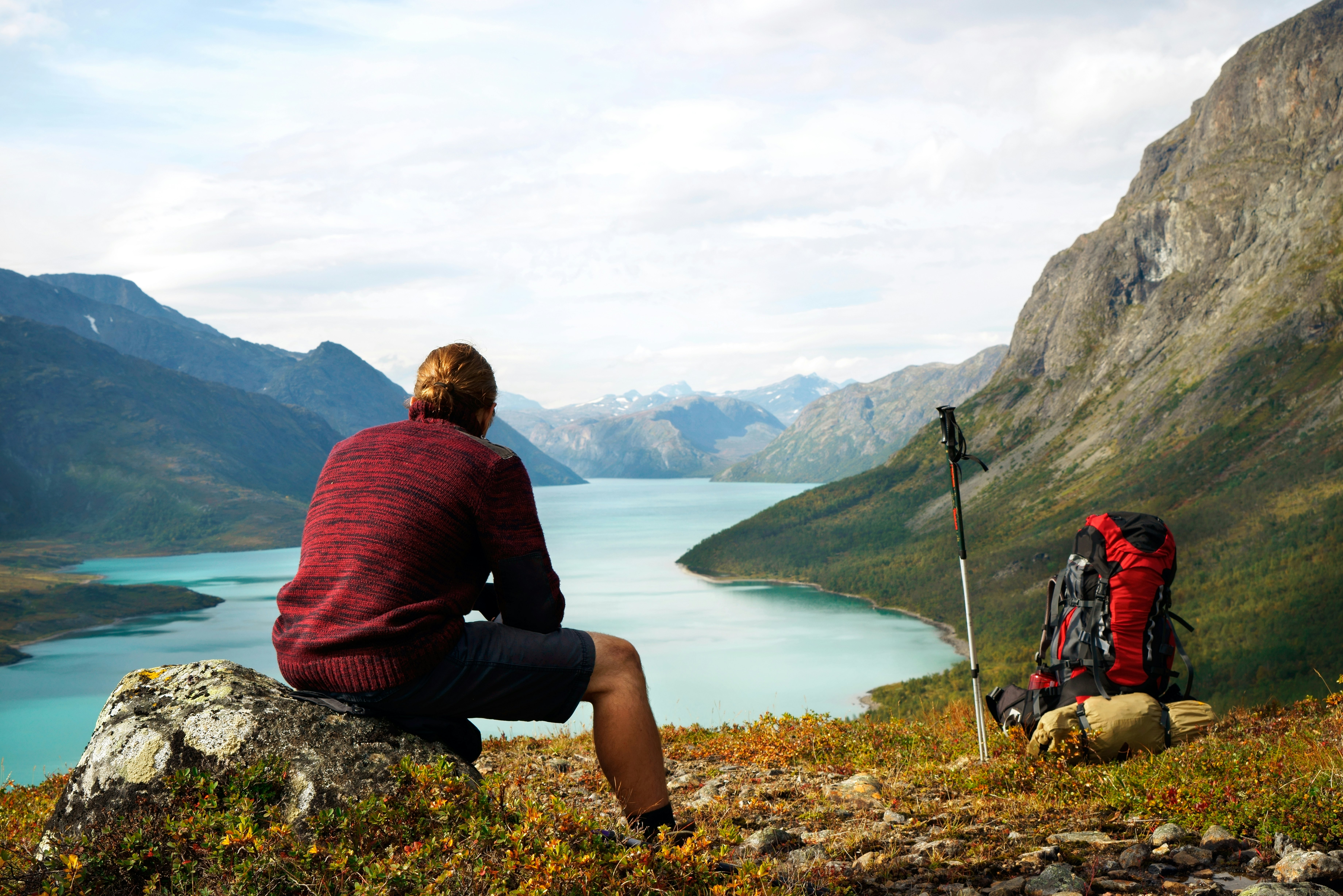 Hiker sitting on a rock in front of Gjendesee Lake in Jotunheimen National Park.