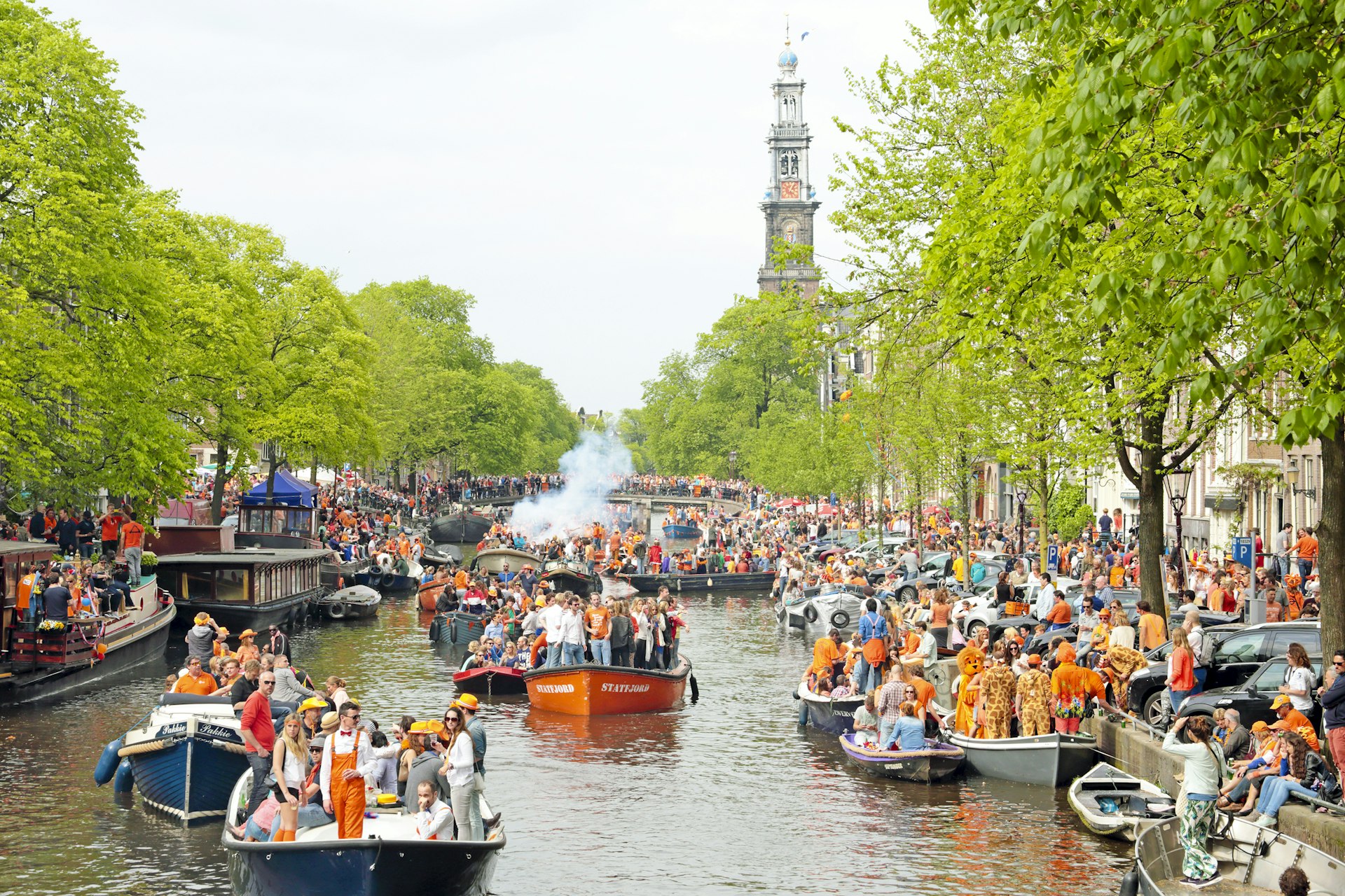 Amsterdam canals full of boats with people dressed in orange to celebrate King's Day