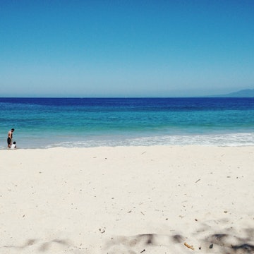 People Enjoying In Sea At Beach Against Clear Sky